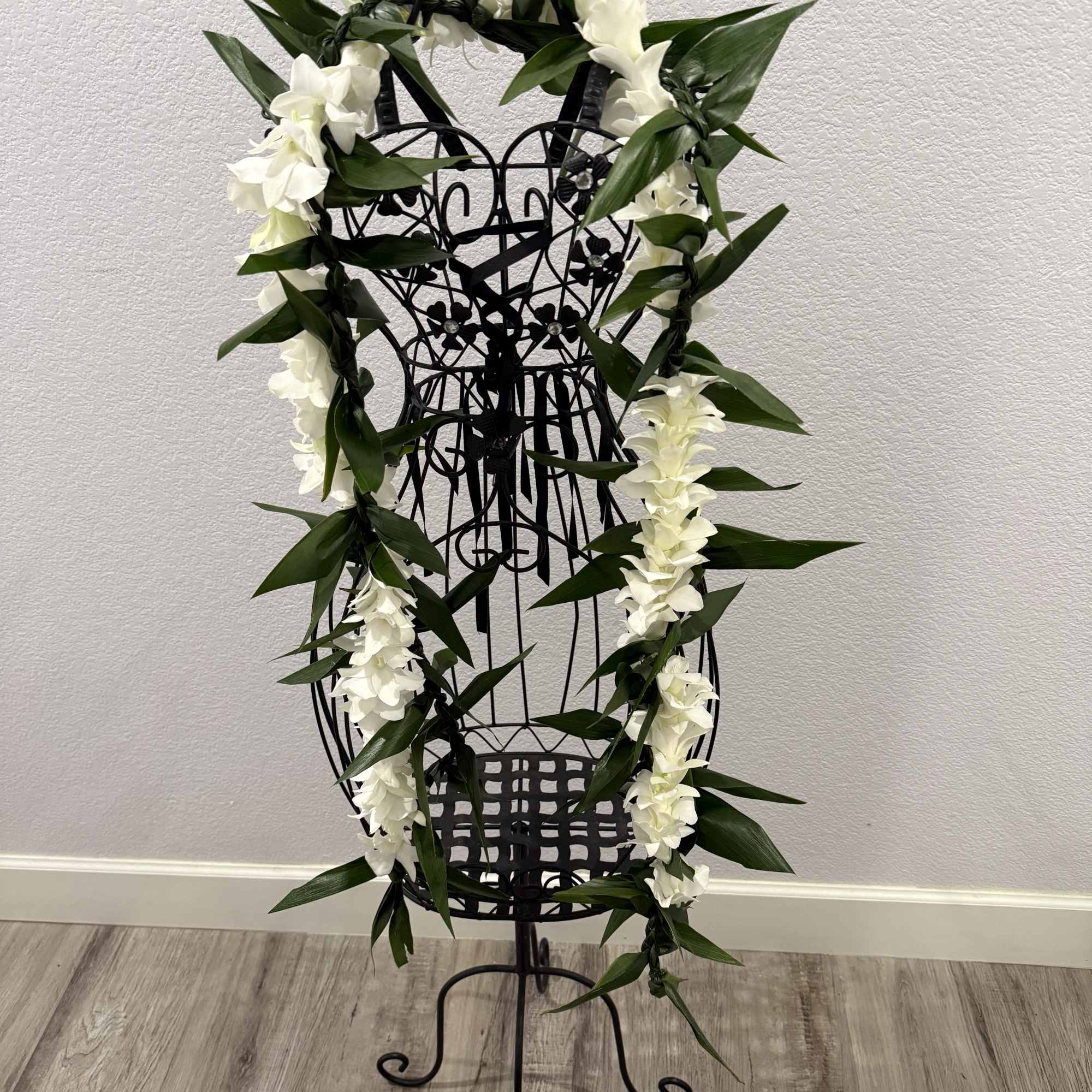 A long white orchid and ti leaf lei draped in a vertical