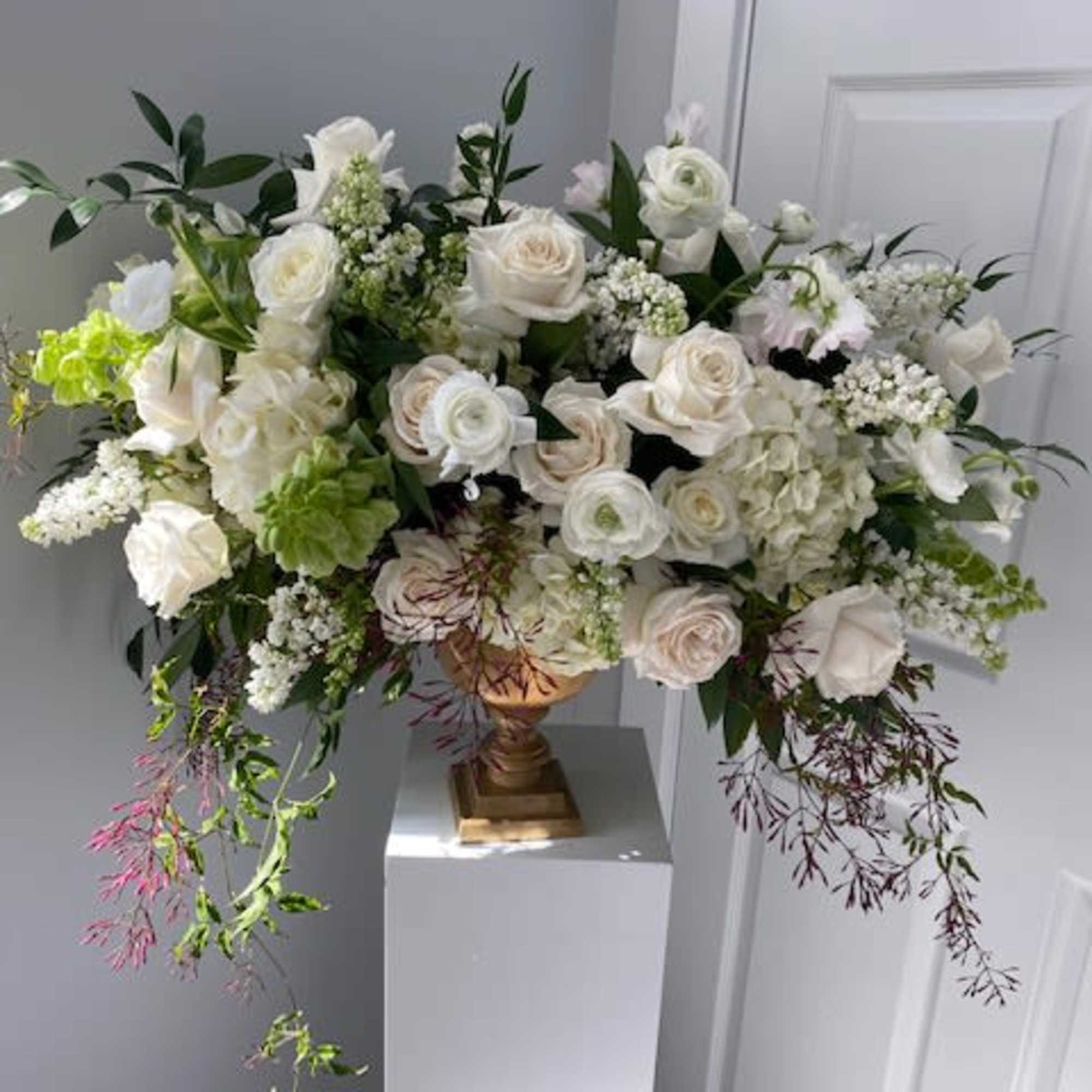Large white floral arrangement in a gold vase