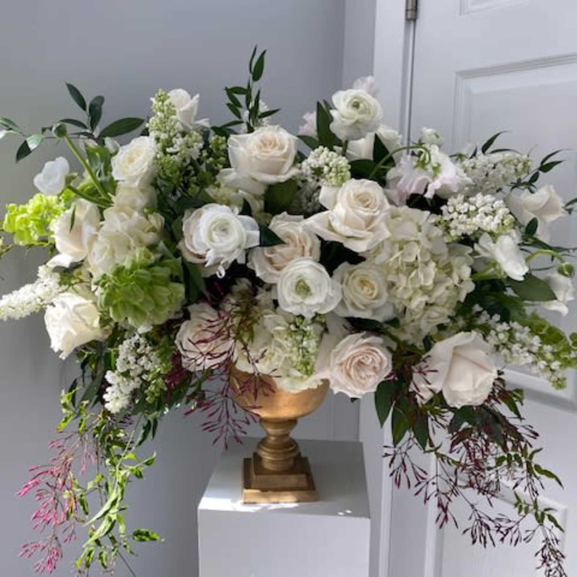 Large white floral arrangement in a gold urn vase