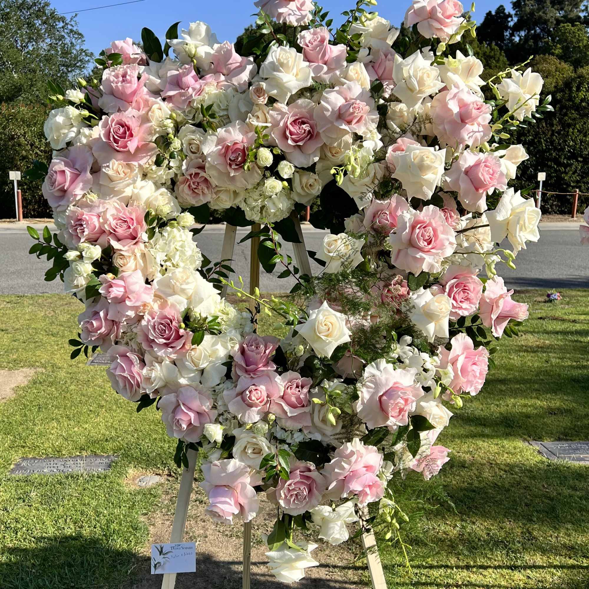 Large heart-shaped floral wreath of pink and white roses on an easel