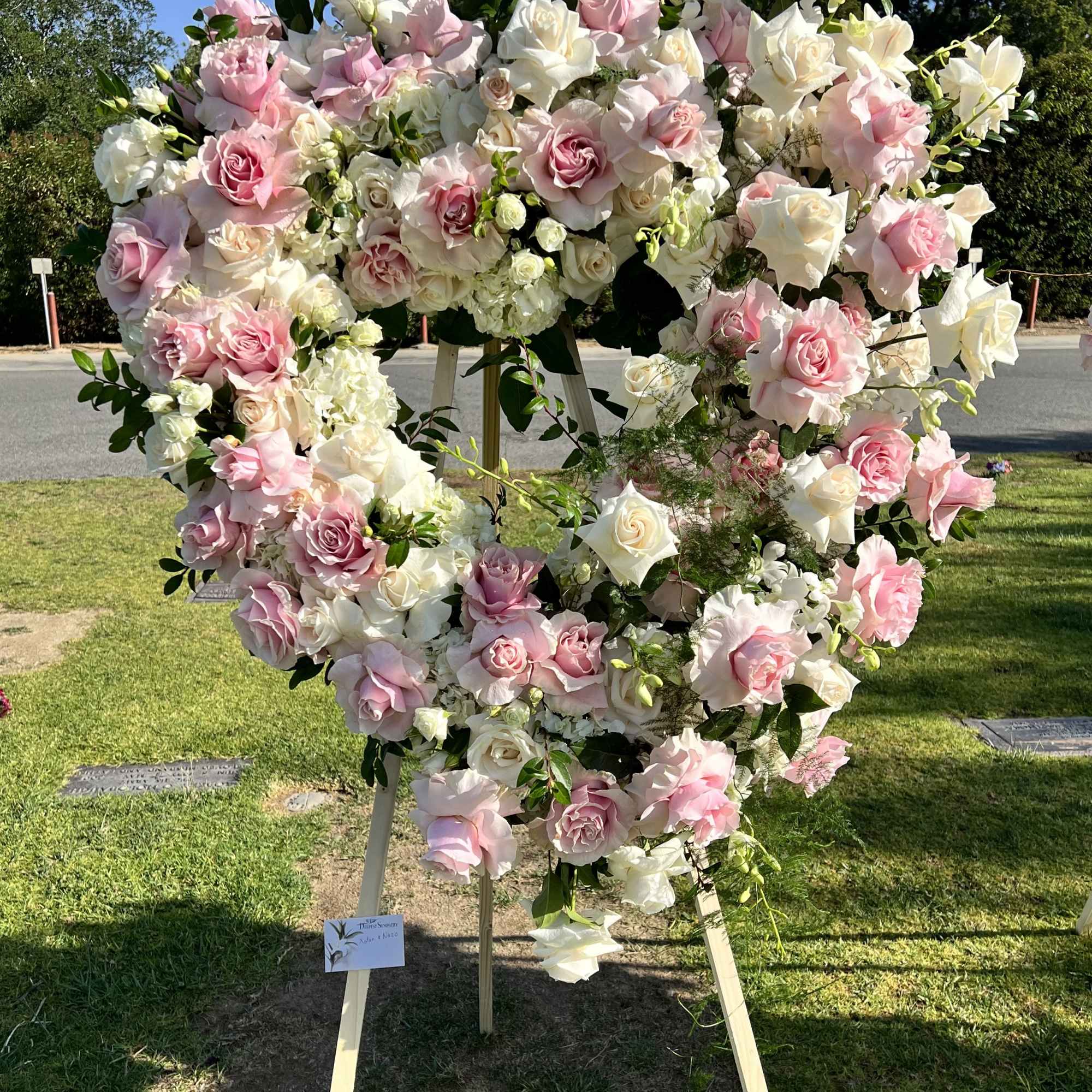 Large heart-shaped floral wreath of pink and white roses on a stand