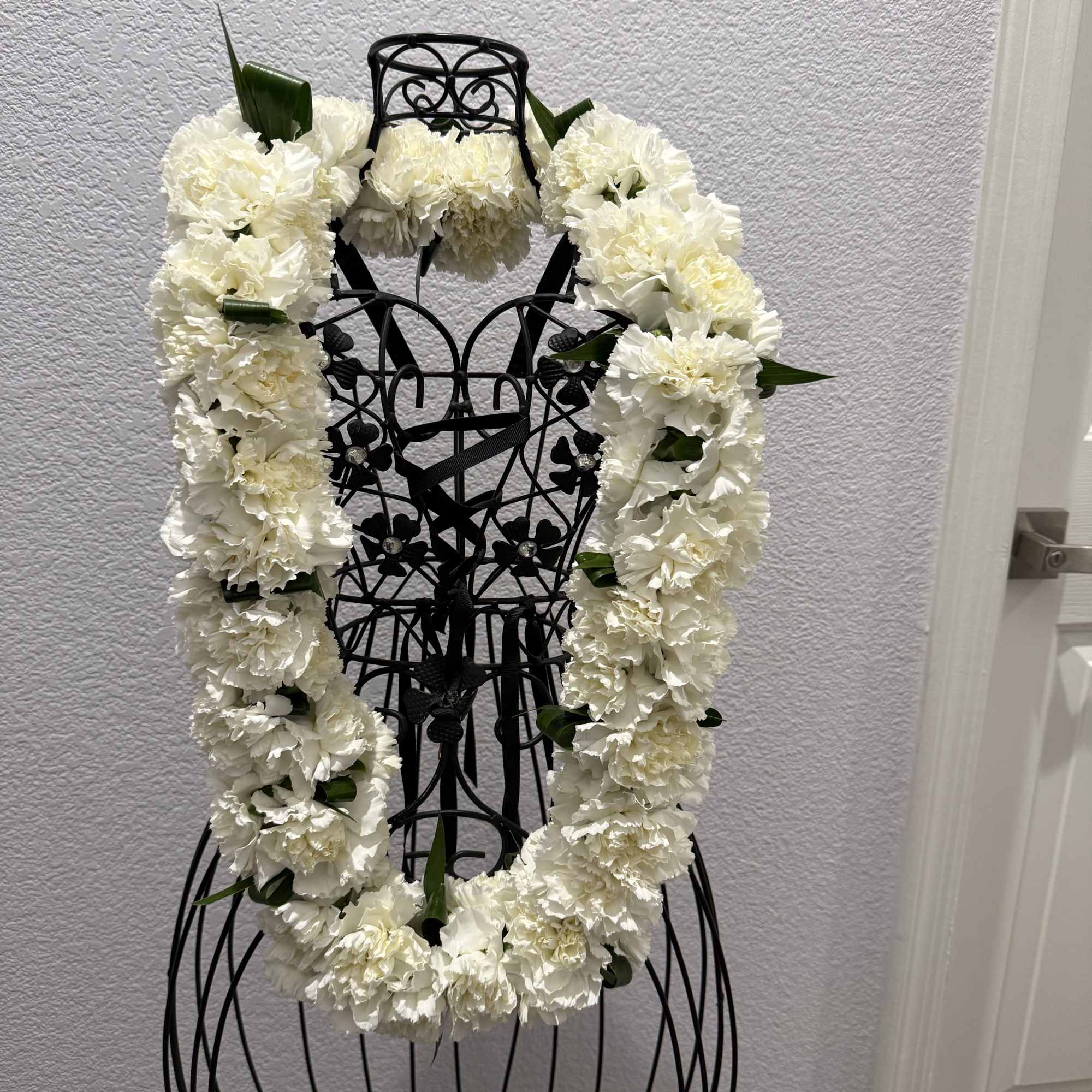 A full, ceremonial white carnation lei creates an immediate sense of reverence