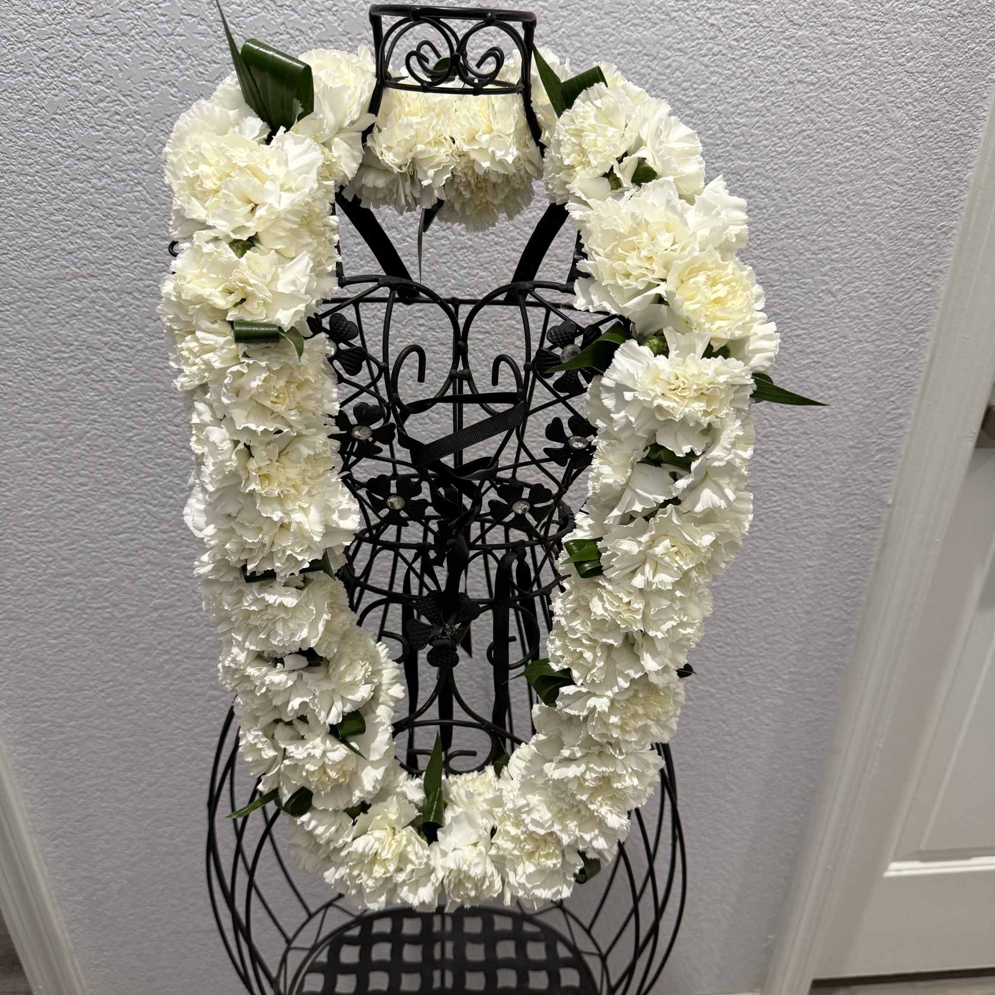A full, ceremonial white carnation lei creates an immediate sense of reverence