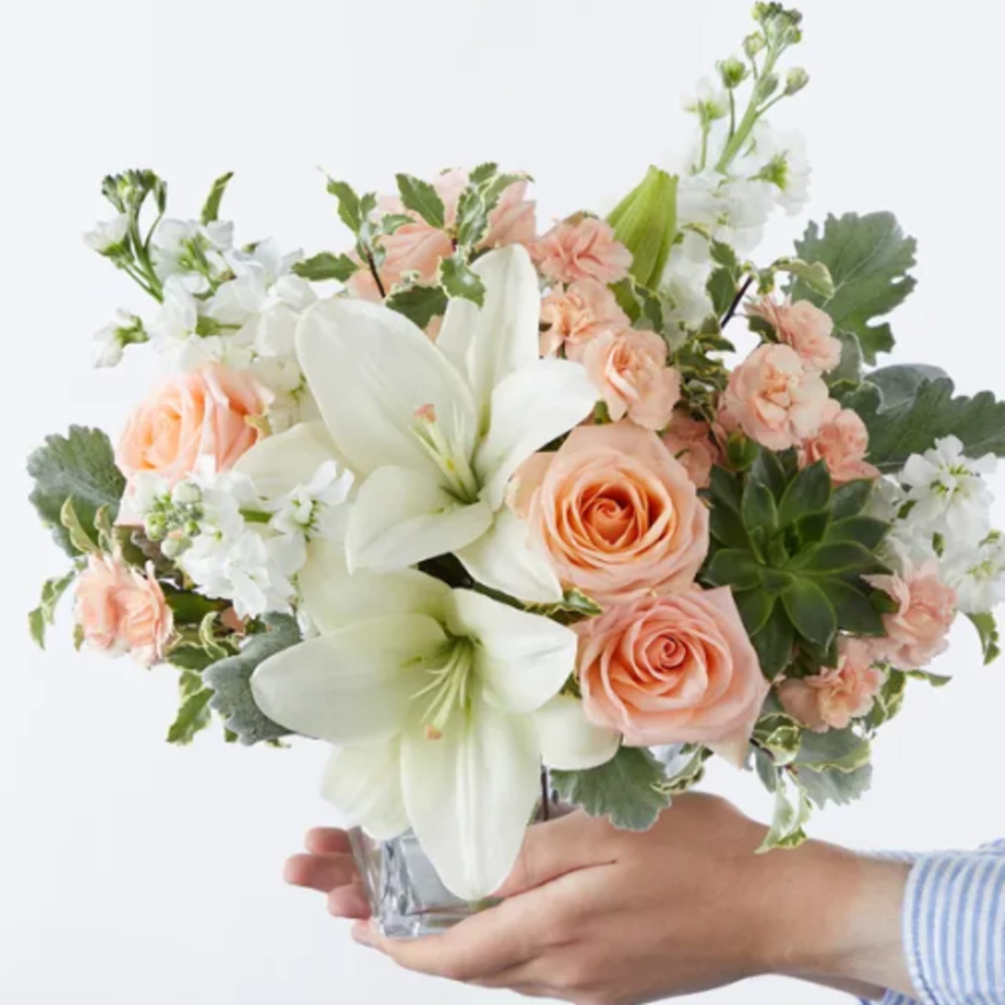 Large white lilies open like soft stars above peach roses and coral-tinged