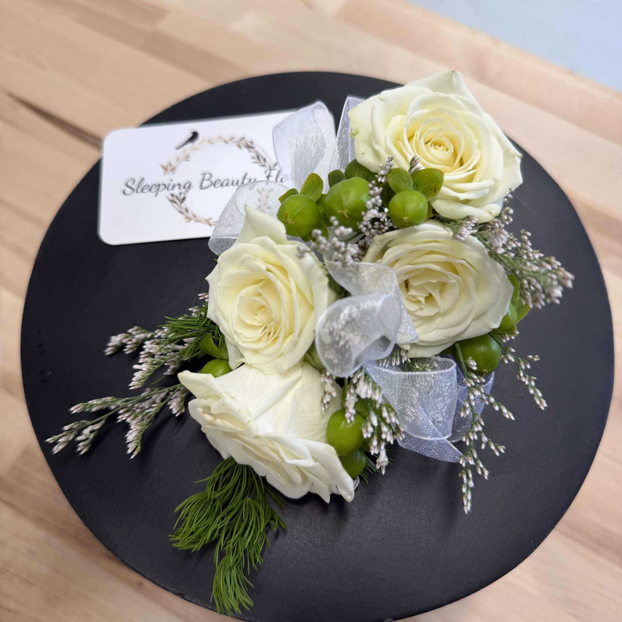 A classic white corsage with silver sheer ribbon, this wrist arrangement looks