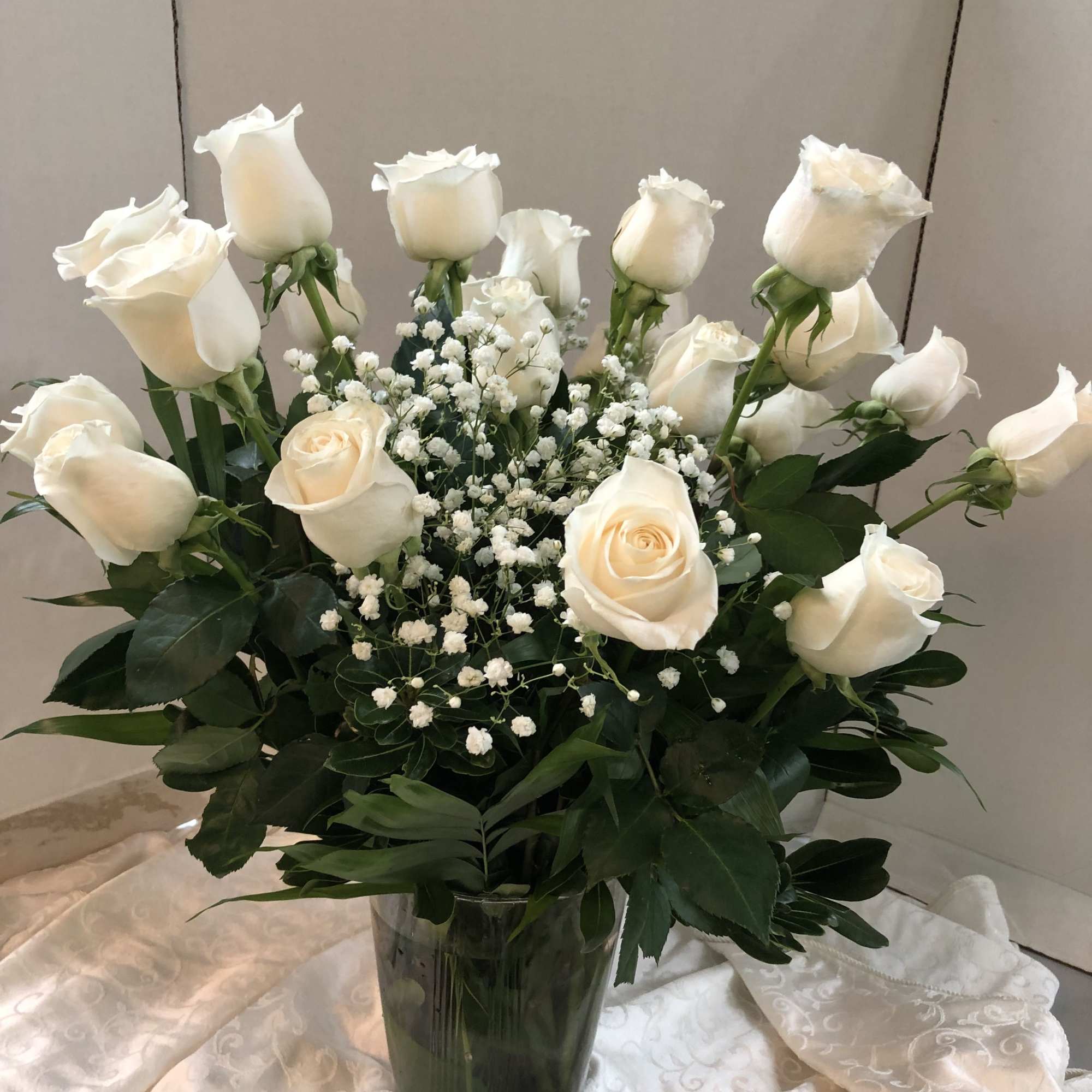 White roses arranged in a glass vase with baby's breath