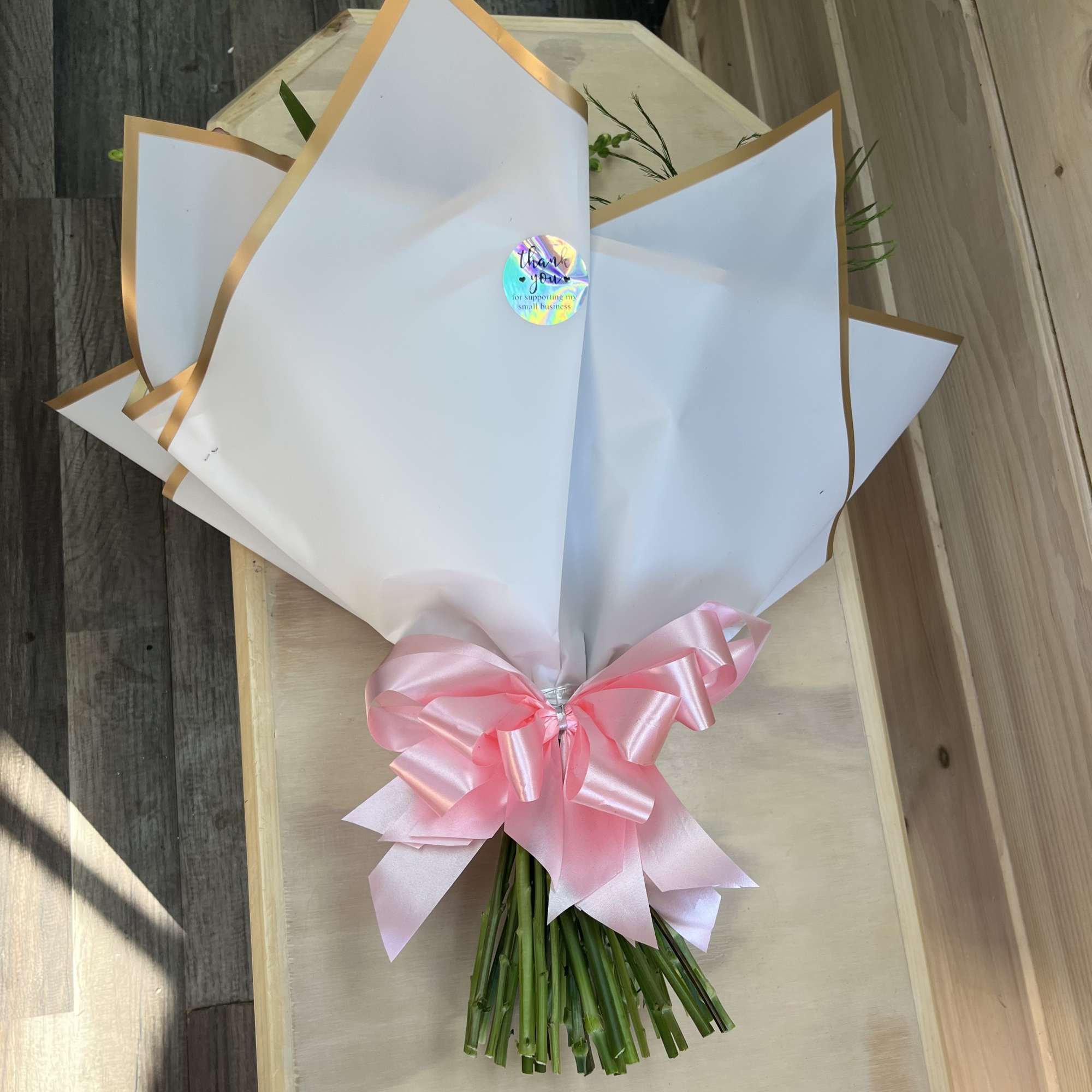 Wrapped bouquet with a pink satin bow and white paper trim