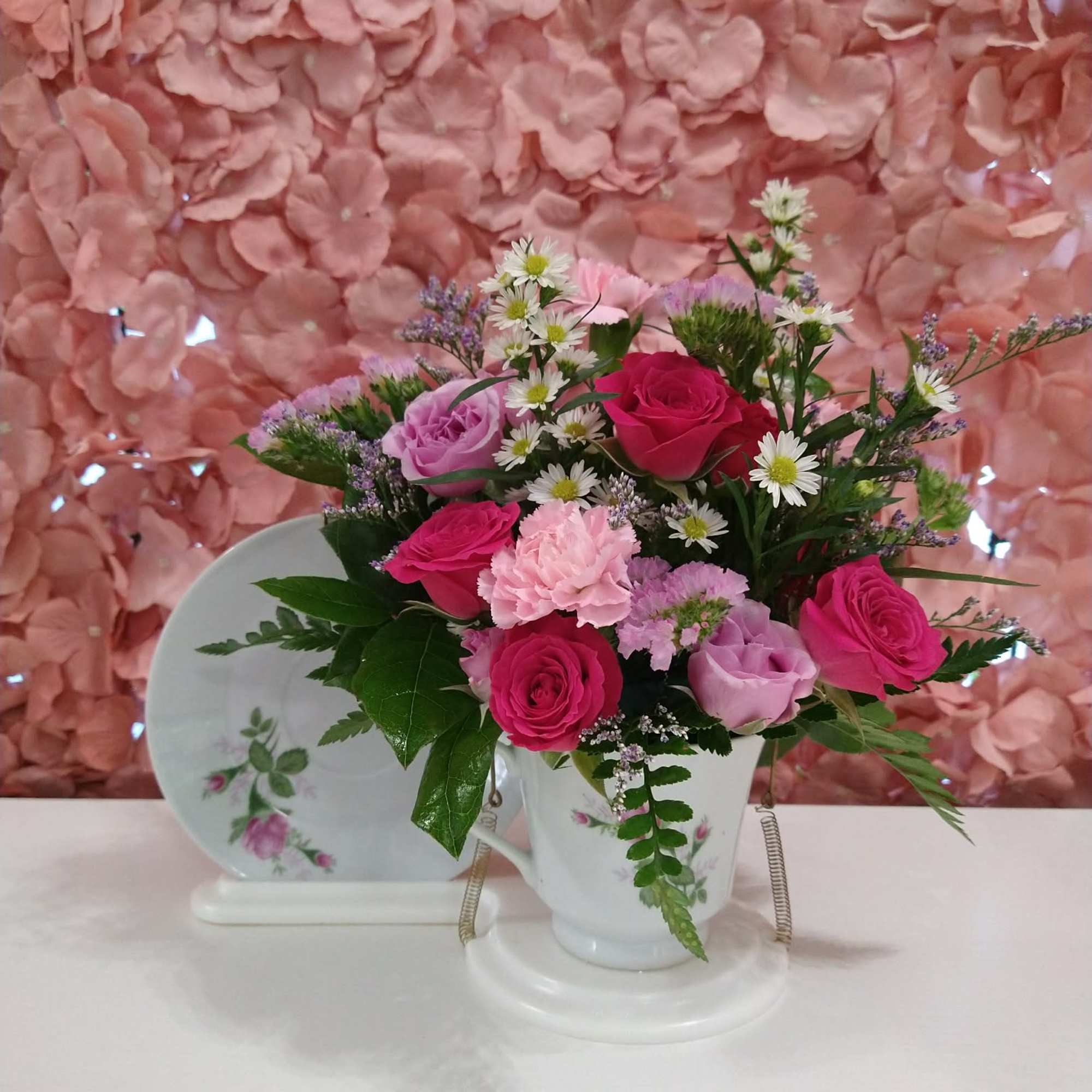 Assorted florals in a porcelain tea cup with a stand to display