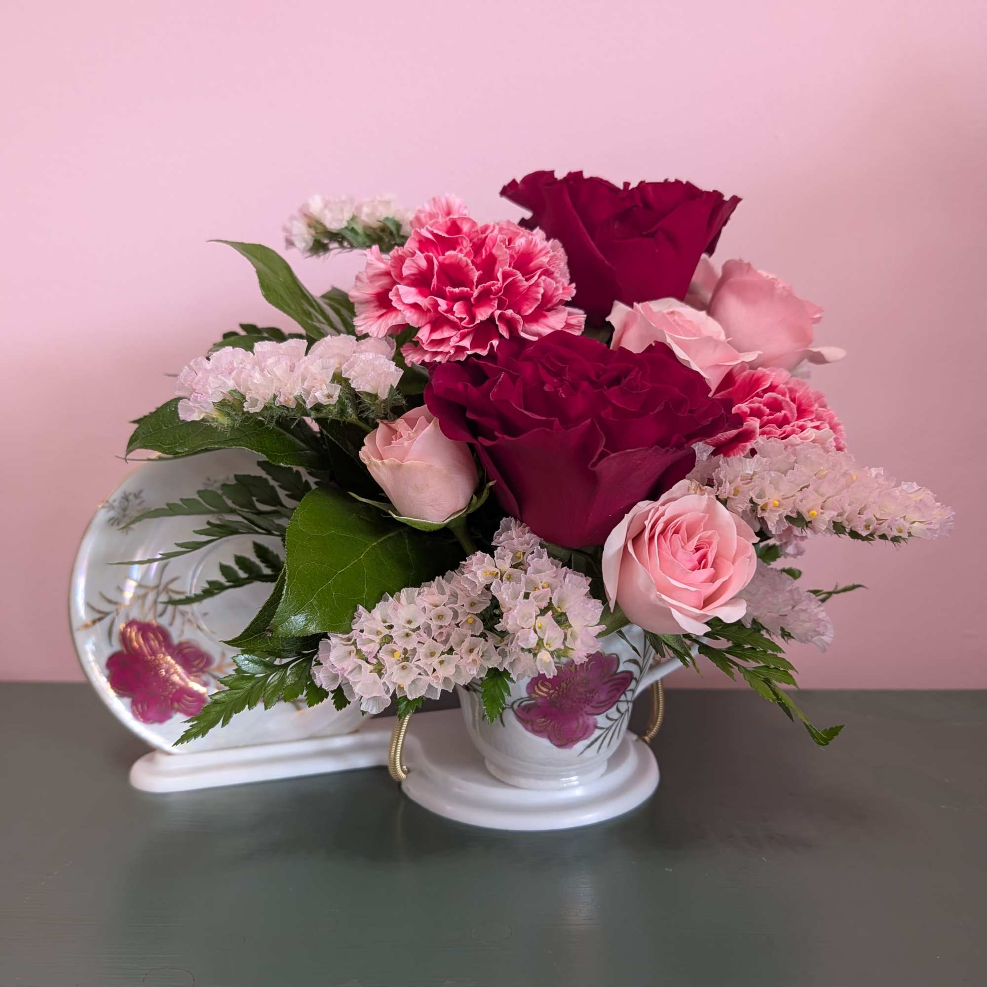 Assorted florals in a porcelain tea cup with a stand to display