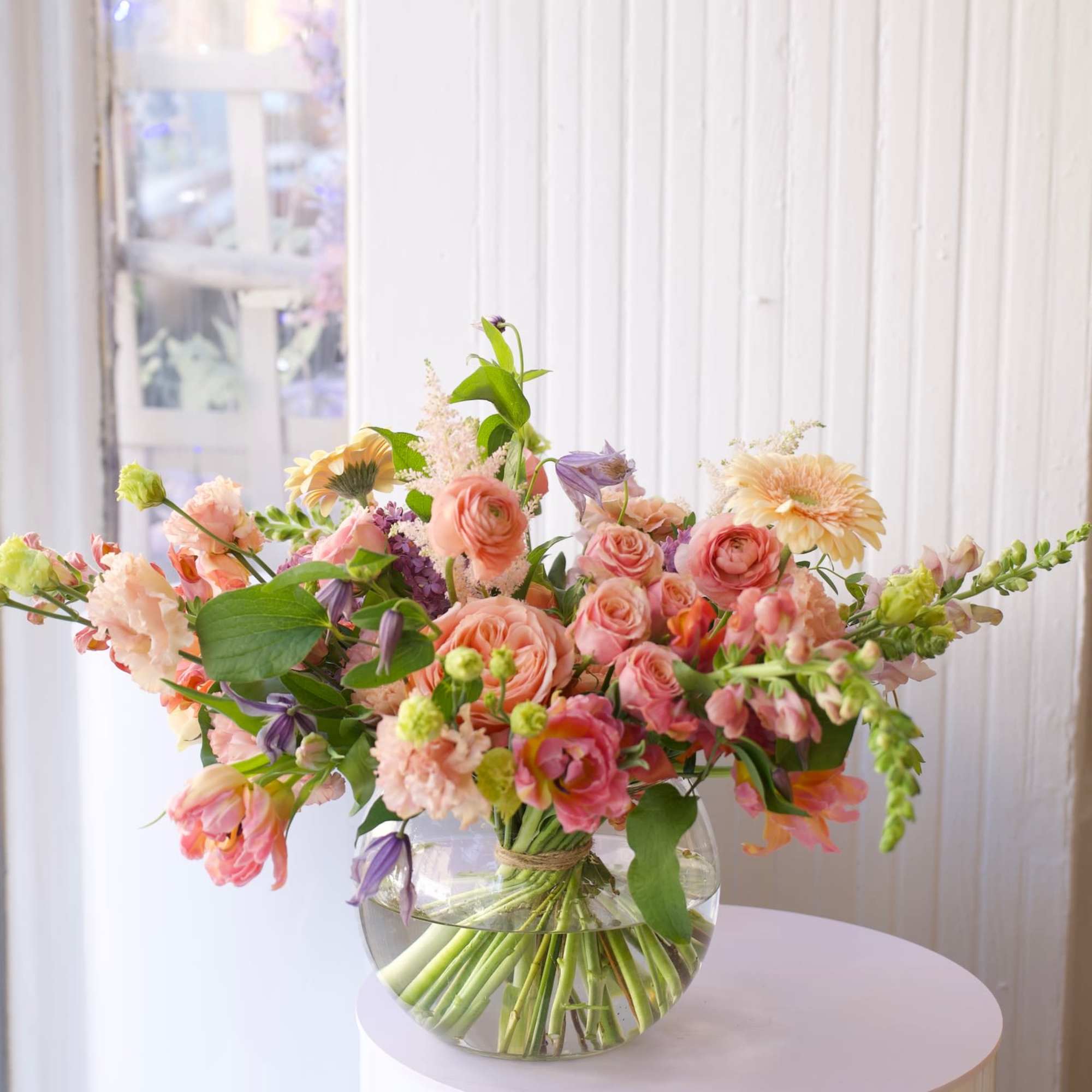 An airy, garden-style floral arrangement featuring peach garden roses, ranunculus, tulips, snapdragons