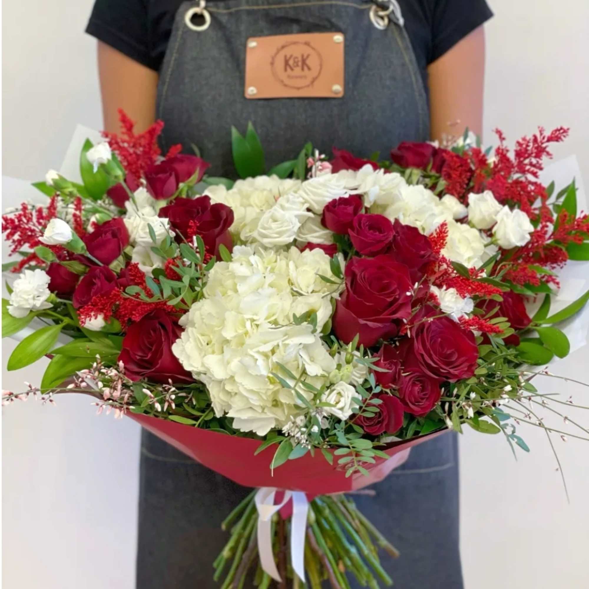 Large bouquet of red roses and white hydrangeas wrapped in red paper