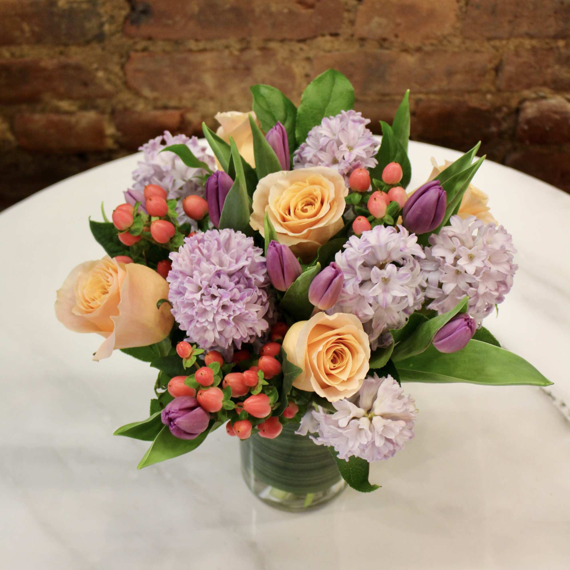 Peach roses and lavender flowers in a glass vase