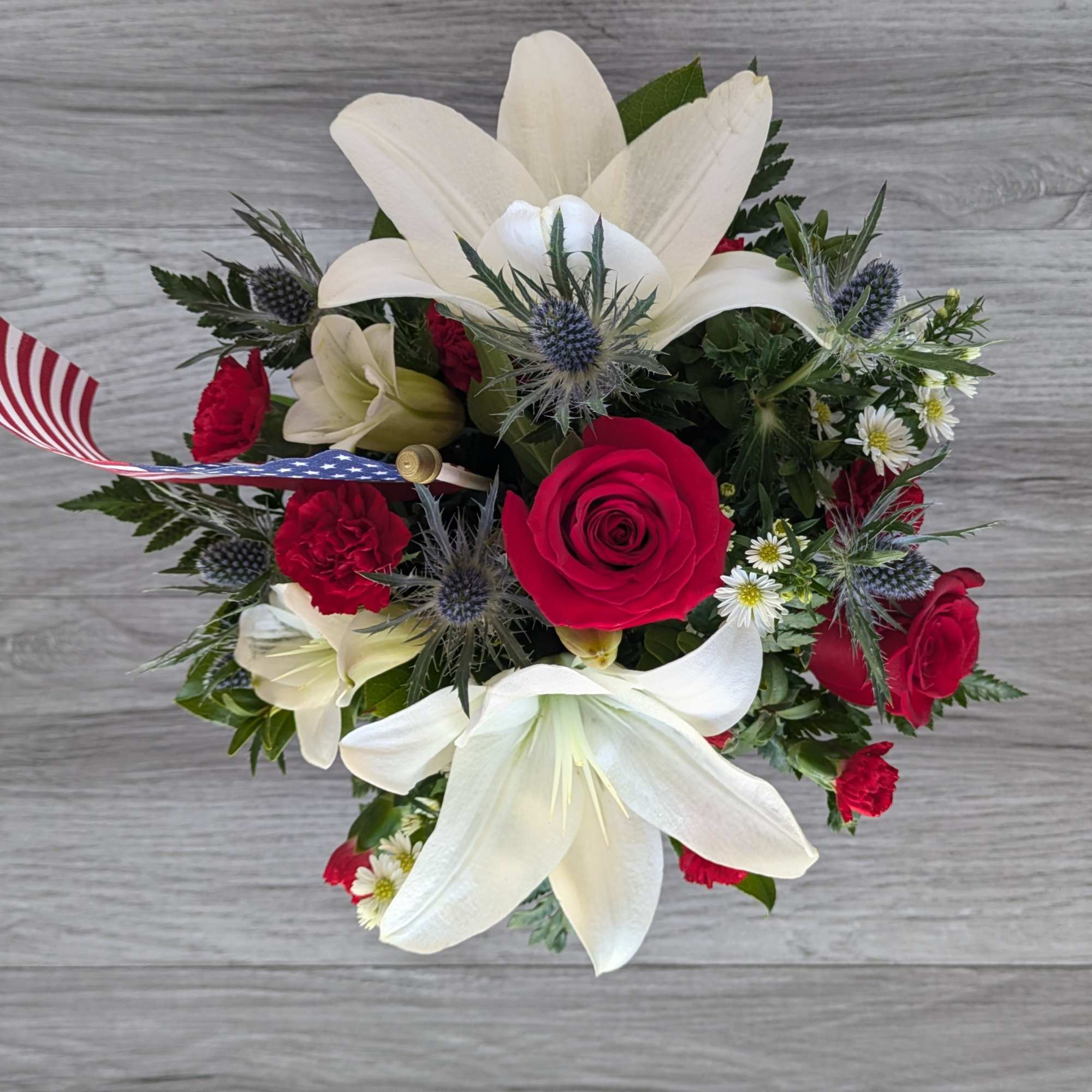 Bouquet of white lilies and red roses with small blue thistles
