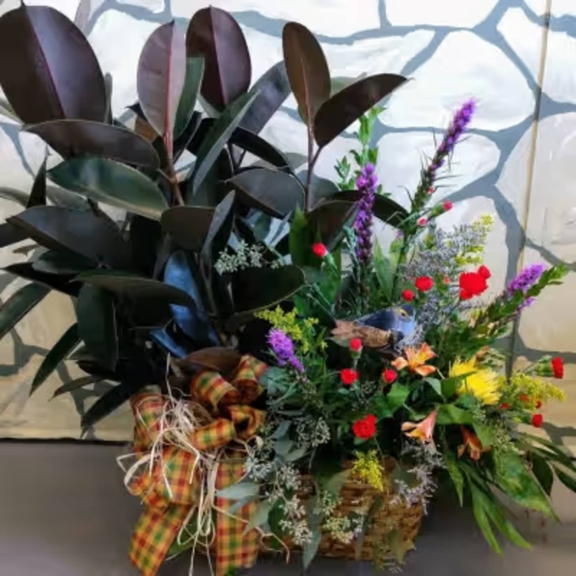 Mixed floral basket with dark rubber plant leaves and colorful wildflowers