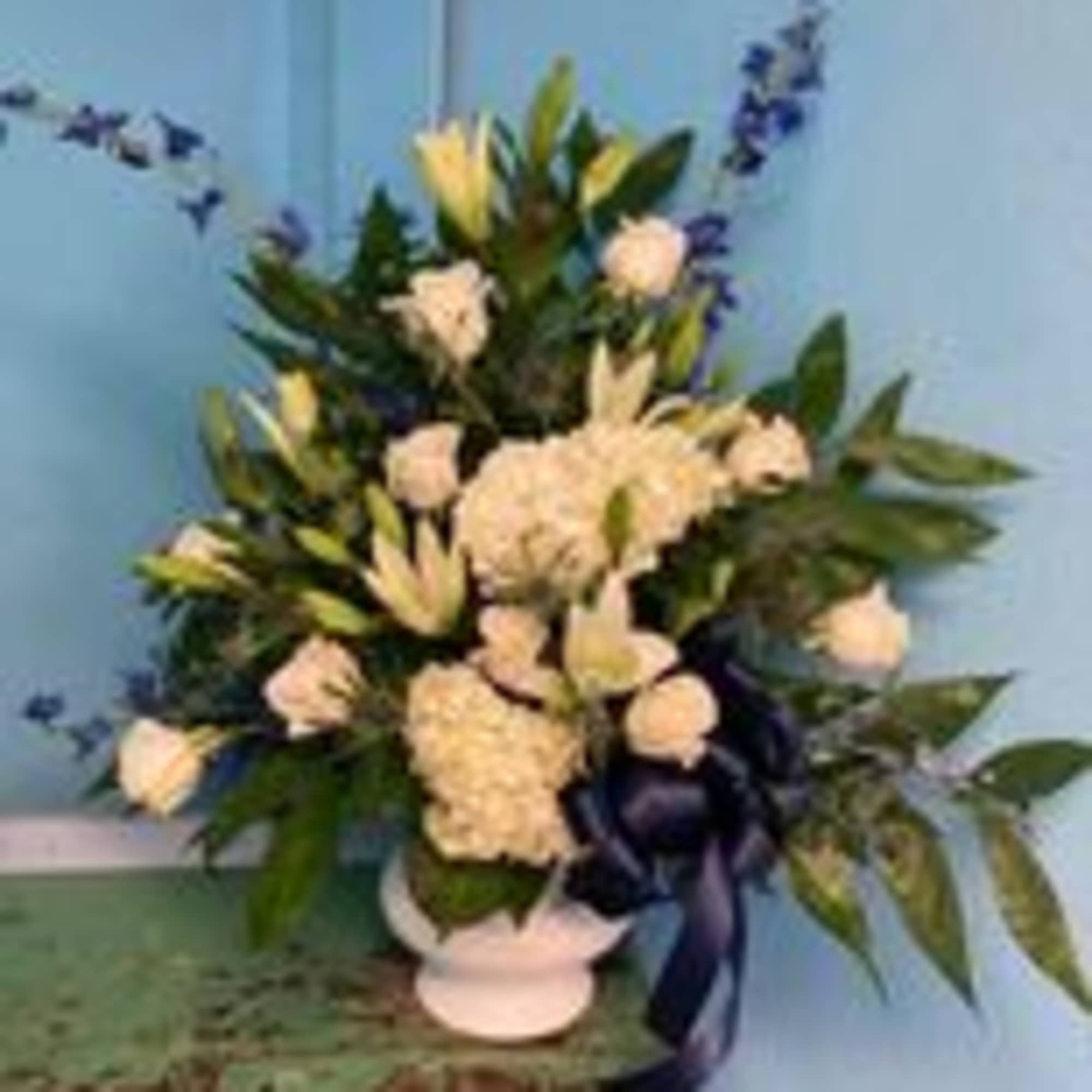 White floral arrangement in a vase with blue ribbon accents