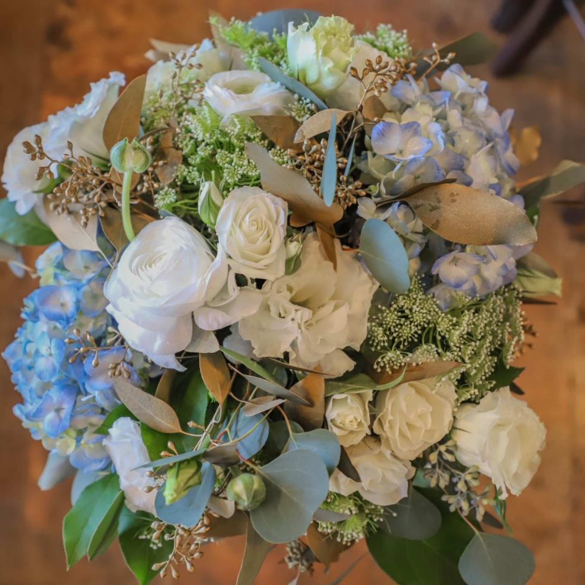 Bouquet of white and pale blue flowers with eucalyptus and gold-toned foliage