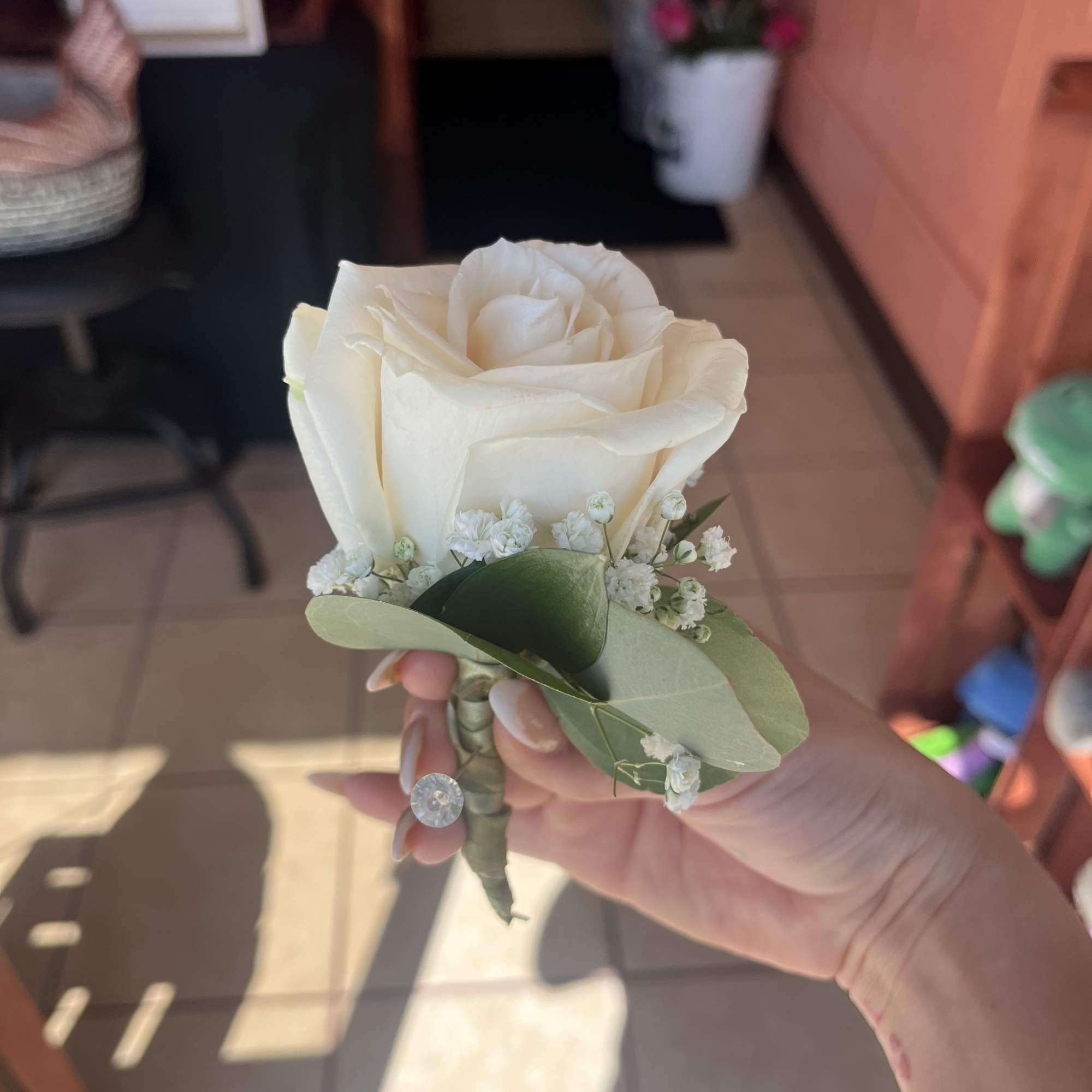 White rose boutonniere with baby's breath and greenery