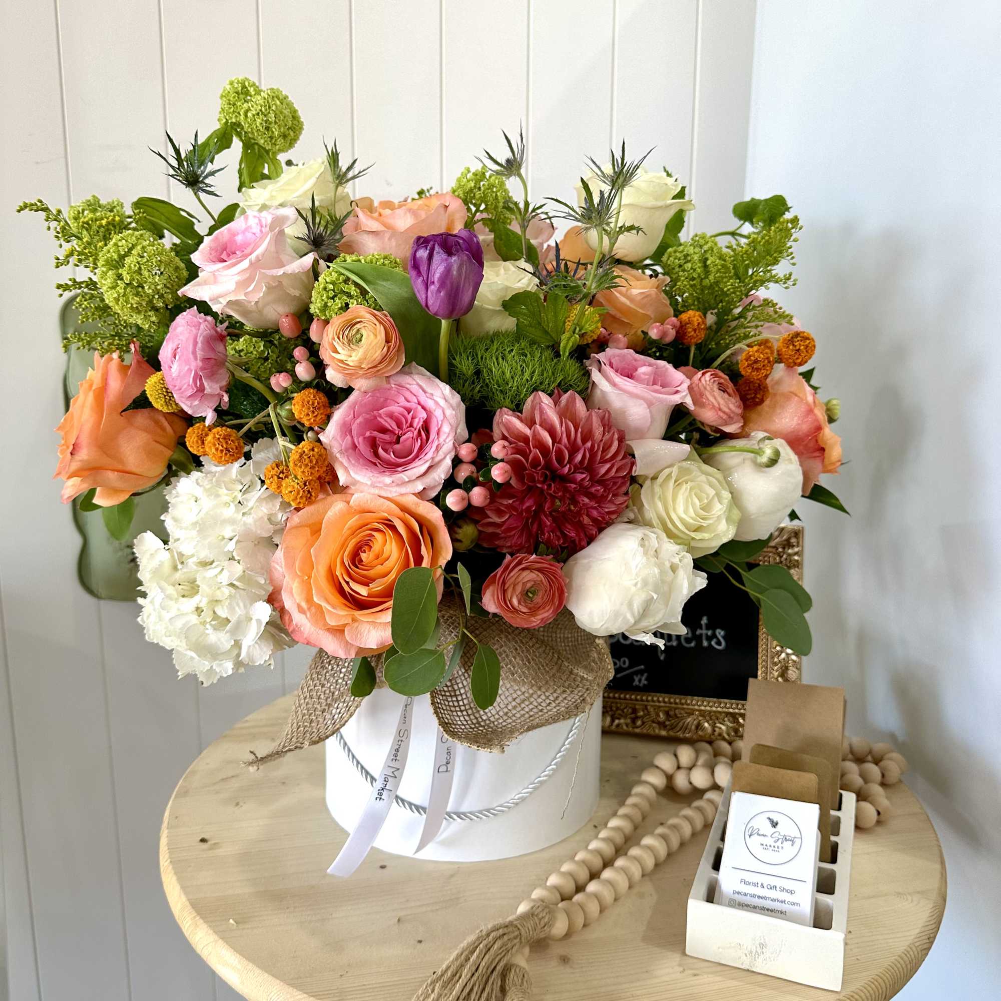 Mixed bouquet in a white hatbox with pink, peach, white, and purple blooms