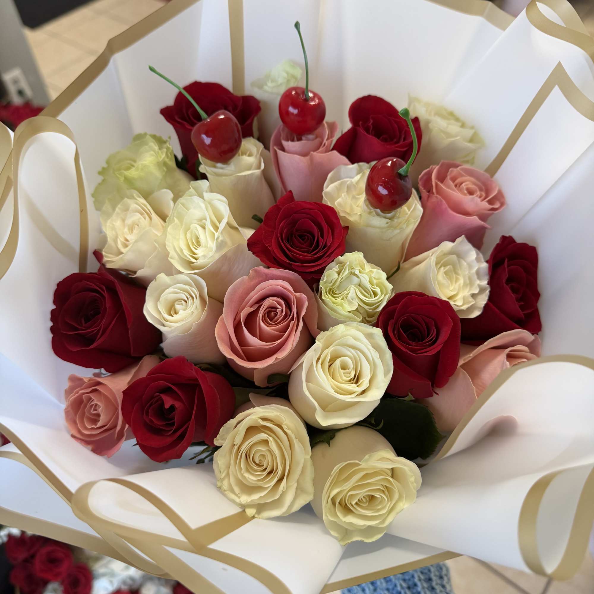 Red, pink and creamy white roses arranged in a lush, rounded bouquet