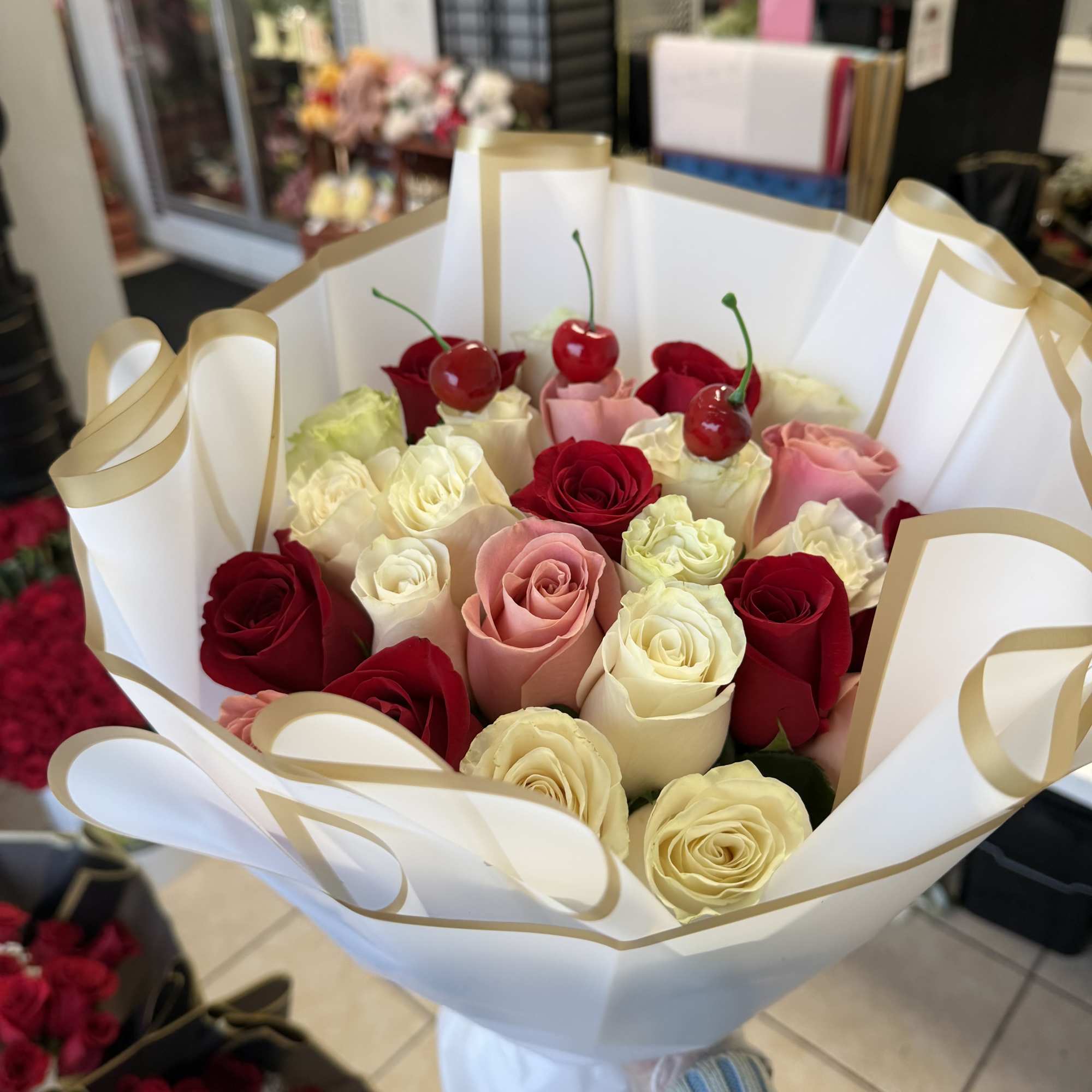 Red, pink and creamy white roses arranged in a lush, rounded bouquet
