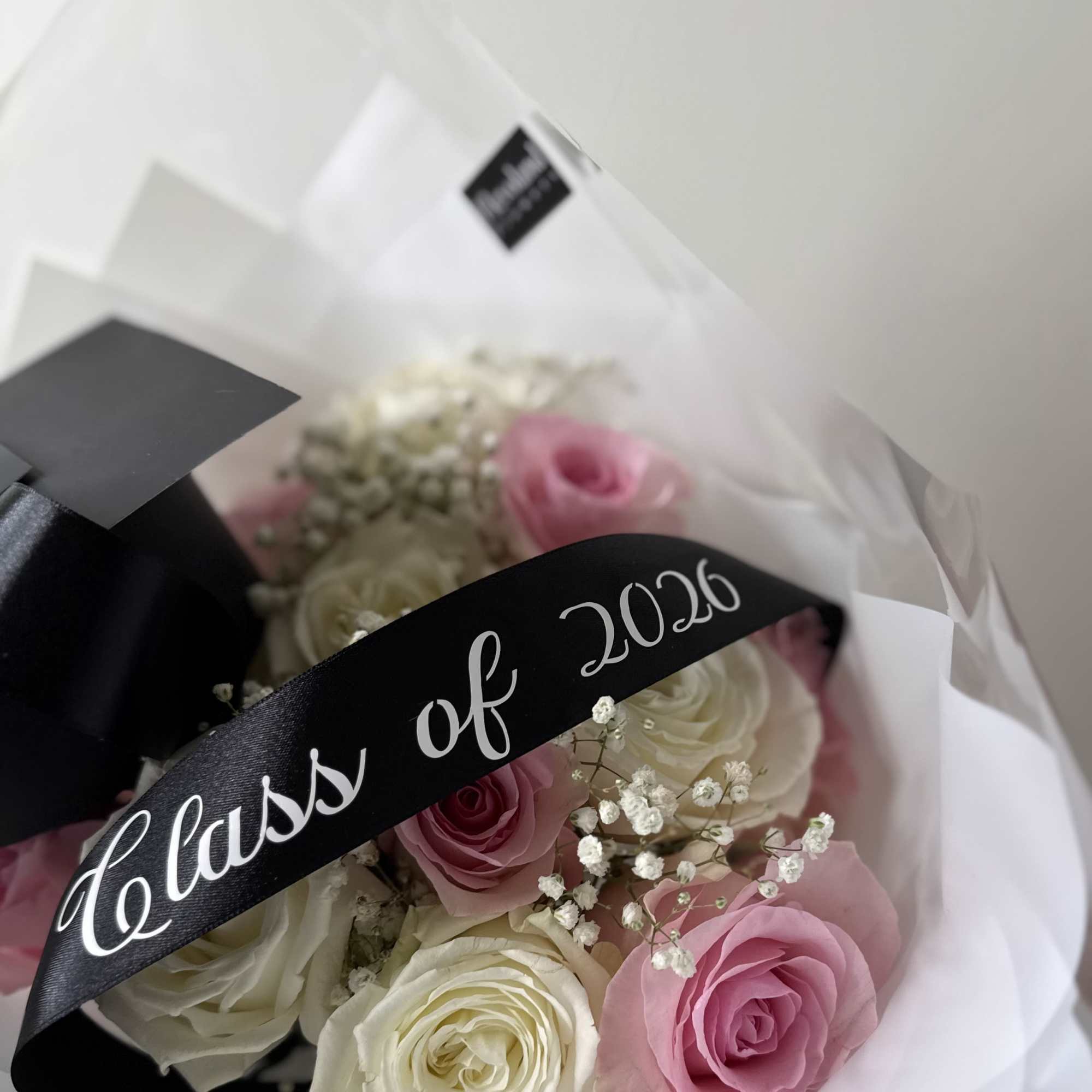 A classic graduation arrangement with soft pink and white roses accented with
