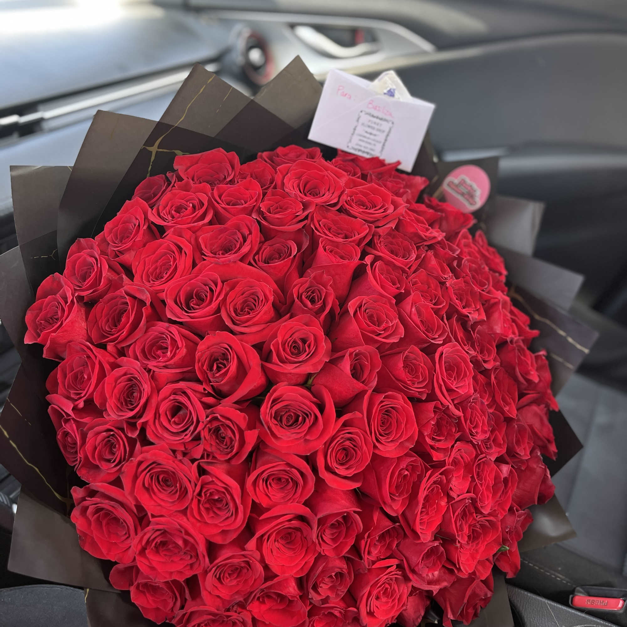 Large bouquet of red roses wrapped in dark paper