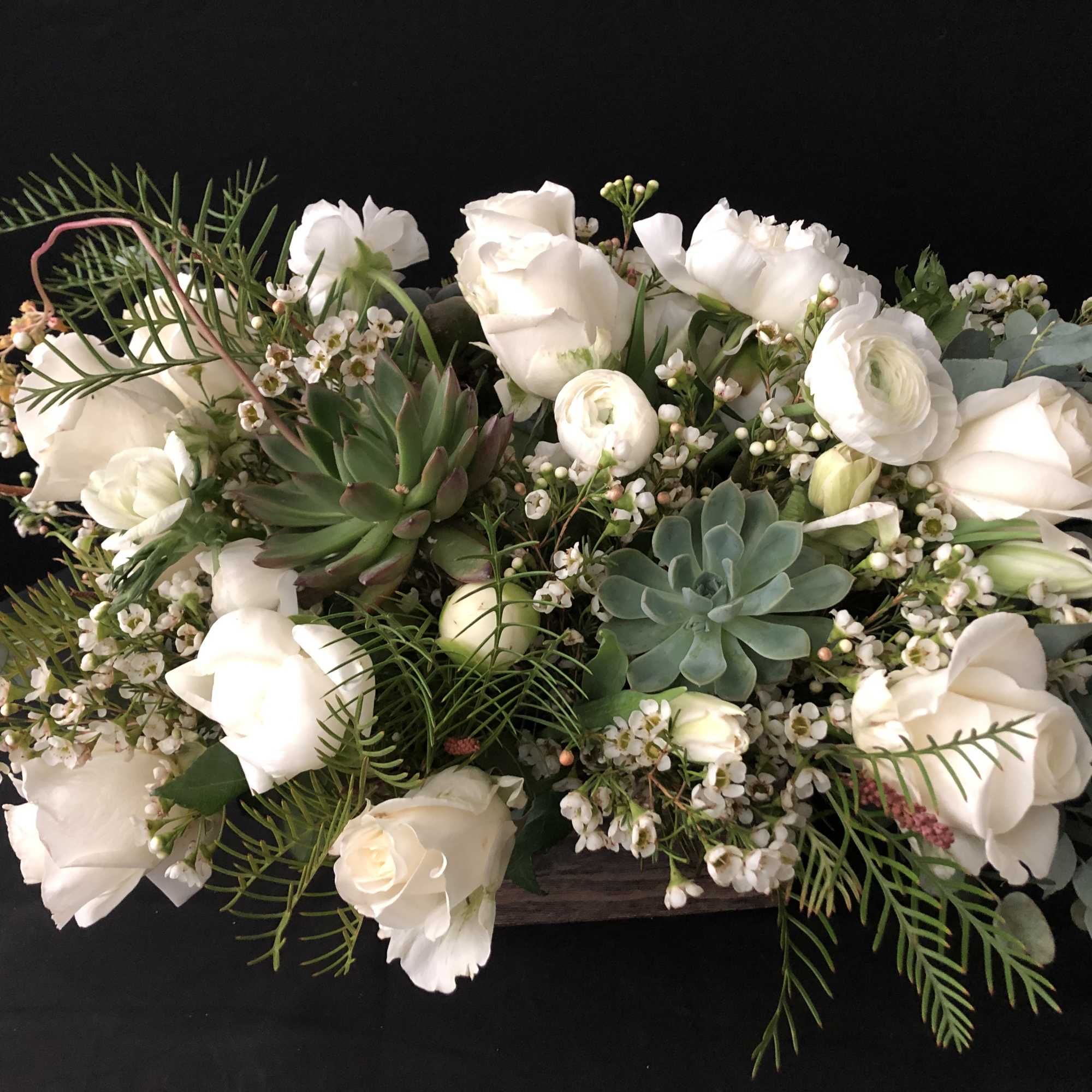 White roses and succulents in a low floral arrangement