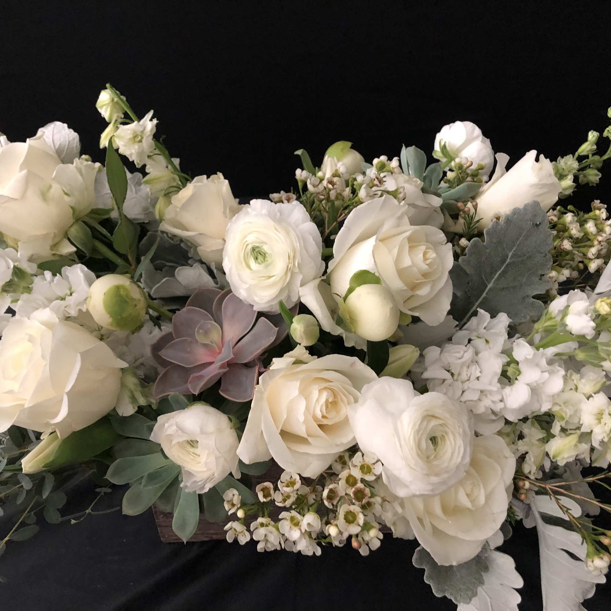 White roses and ranunculus arranged with small white filler flowers