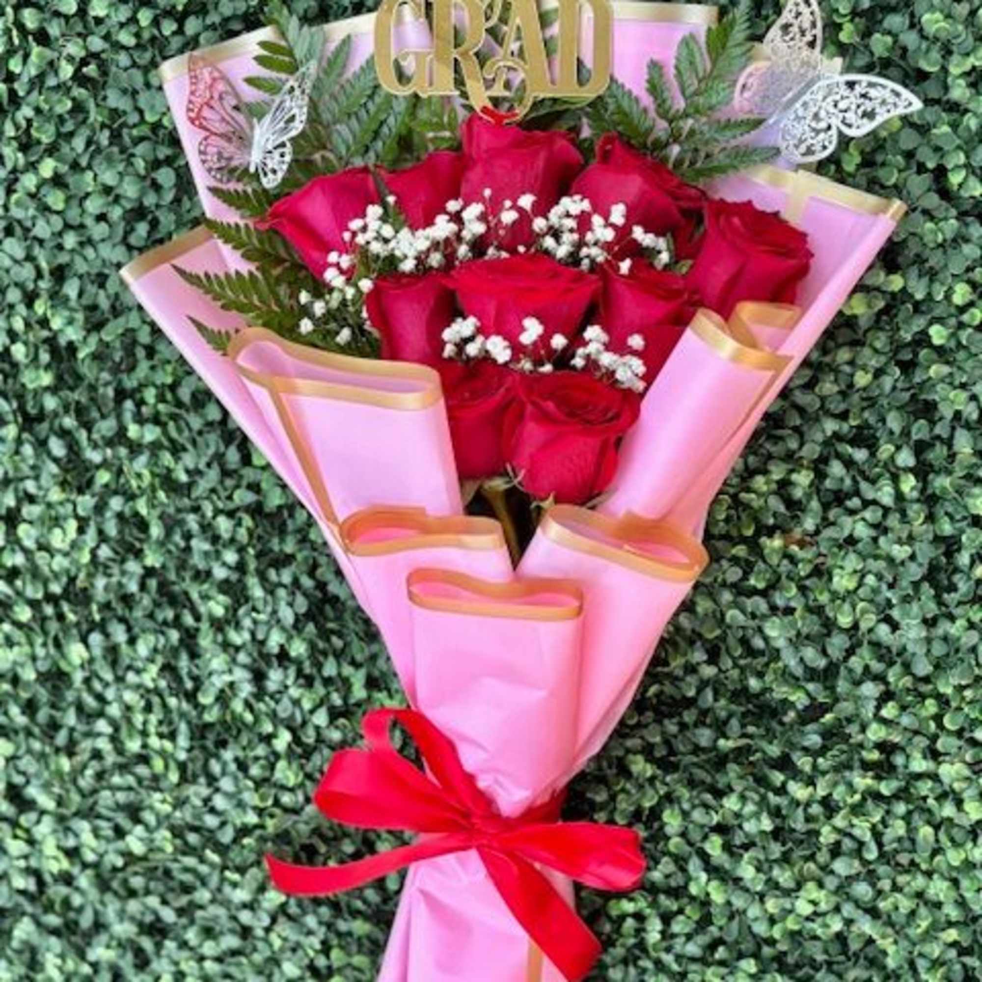 A tight cluster of vivid red roses wrapped in soft pink paper