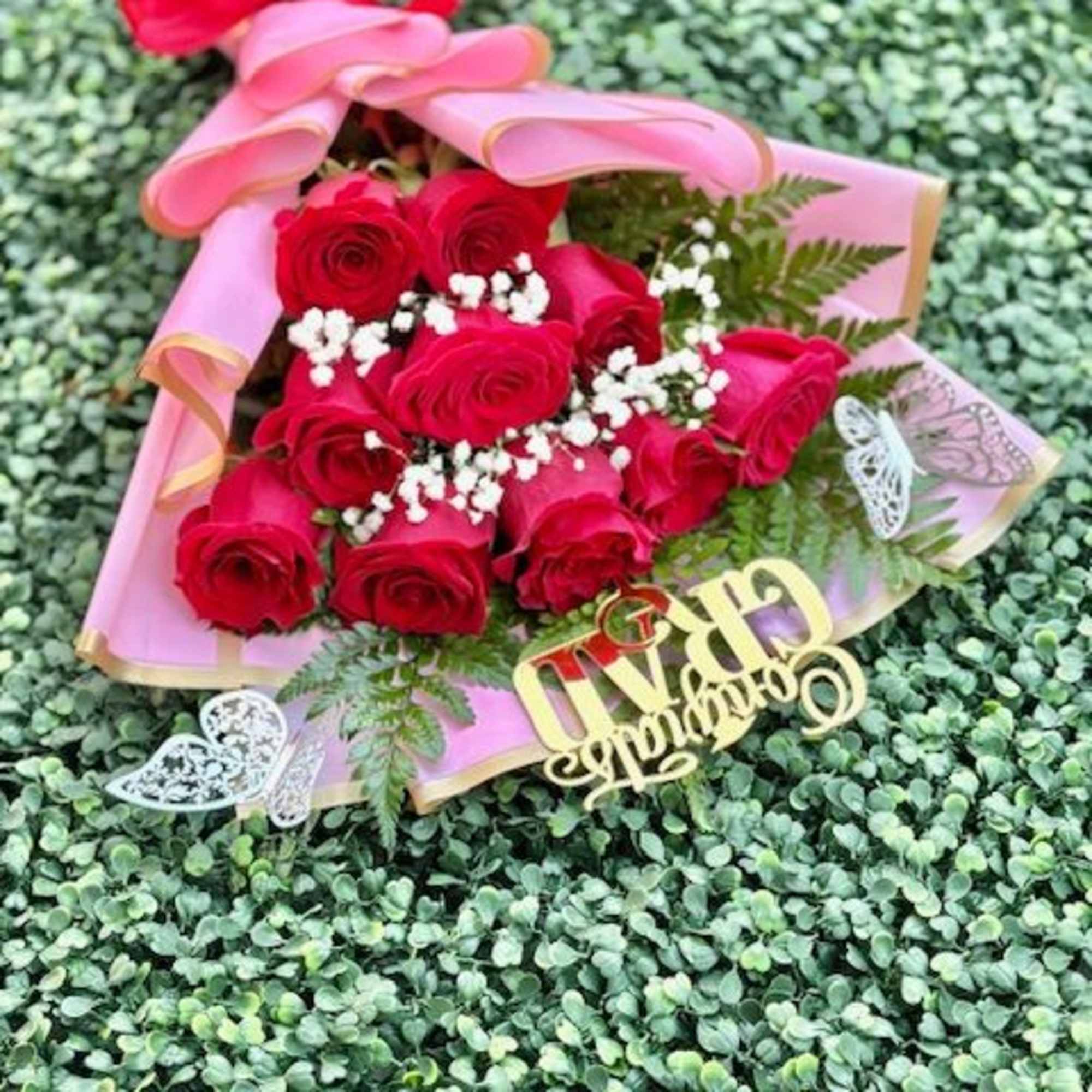 A tight cluster of vivid red roses wrapped in soft pink paper