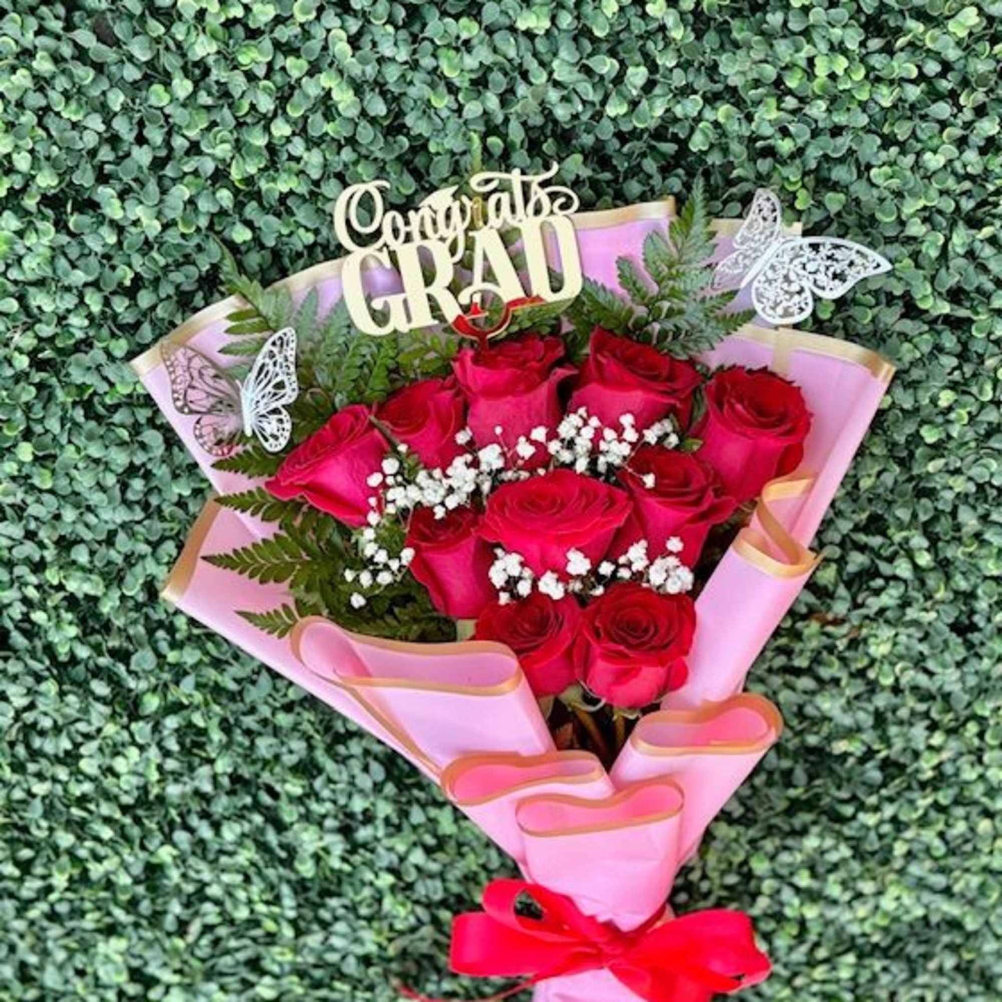 A tight cluster of vivid red roses wrapped in soft pink paper