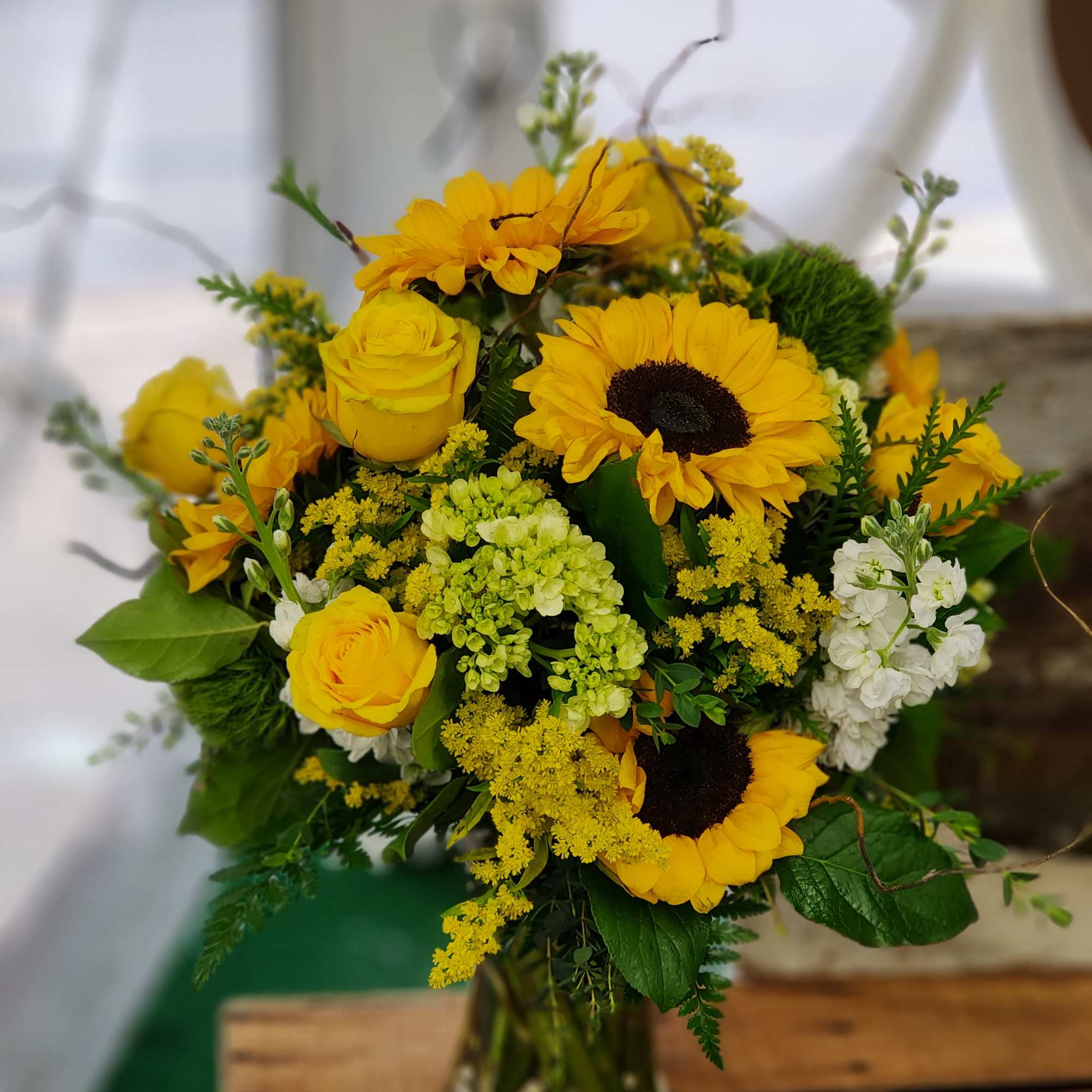 Yellow sunflowers and roses arranged in a glass vase