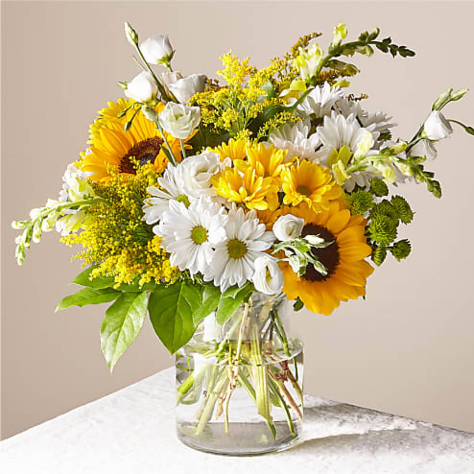 Bouquet of sunflowers, white daisies, and yellow flowers in a glass vase