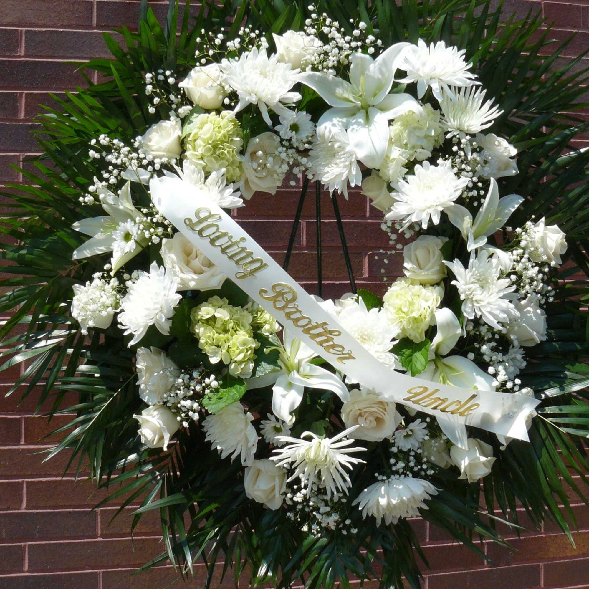 White funeral wreath with lilies, roses, and chrysanthemums on an easel