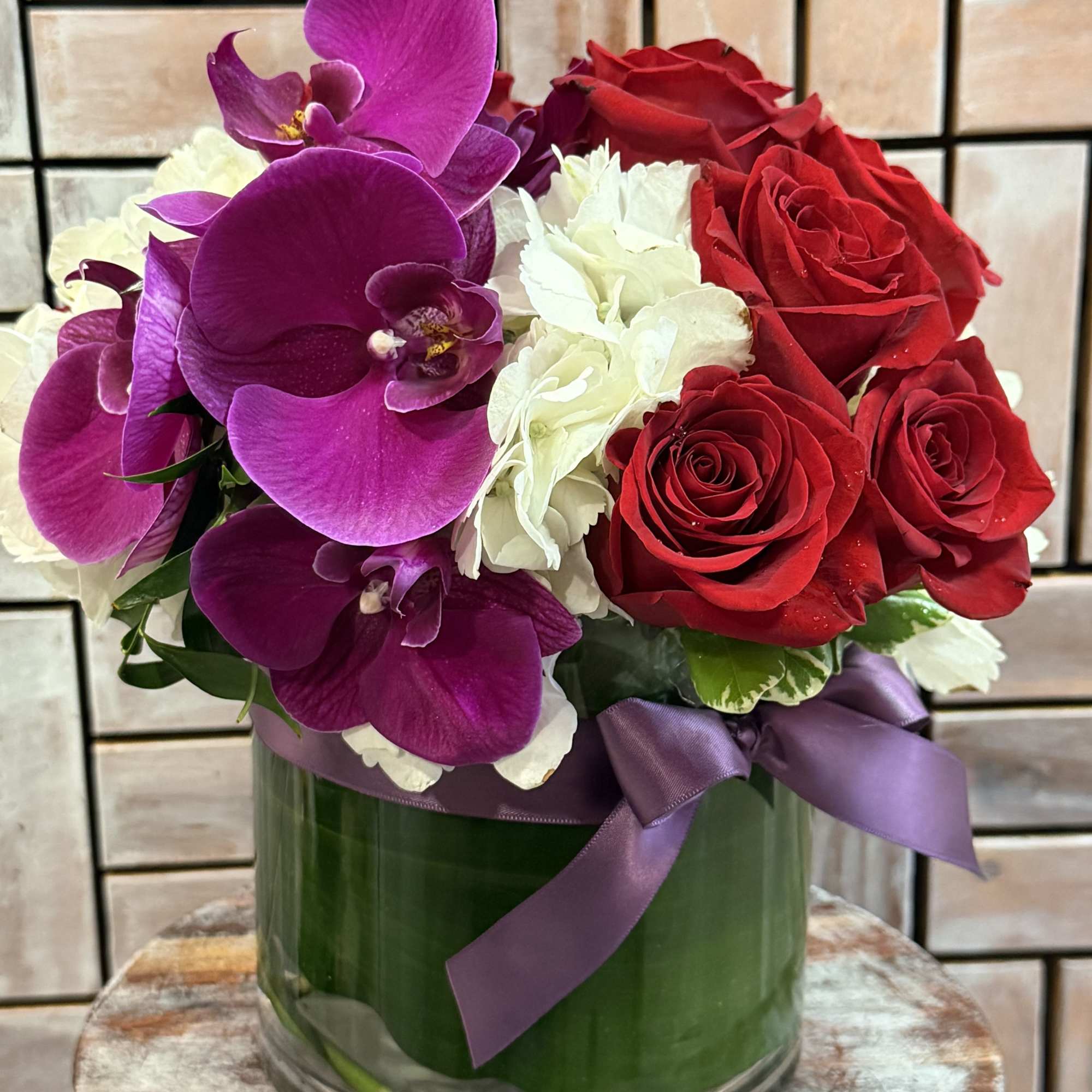 A luxurious arrangement featuring vibrant purple orchids, premium red roses, and soft