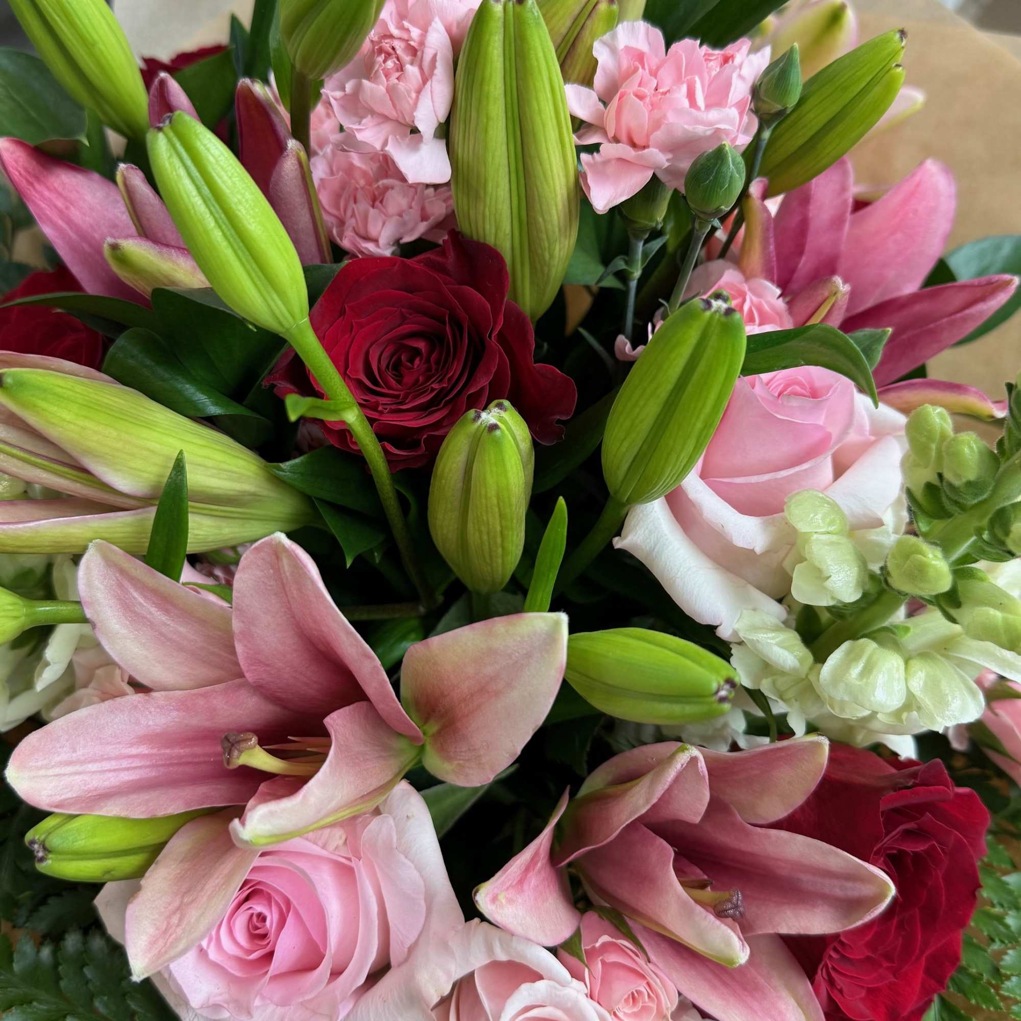 Bouquet of pink lilies, roses, and carnations with a red rose accent