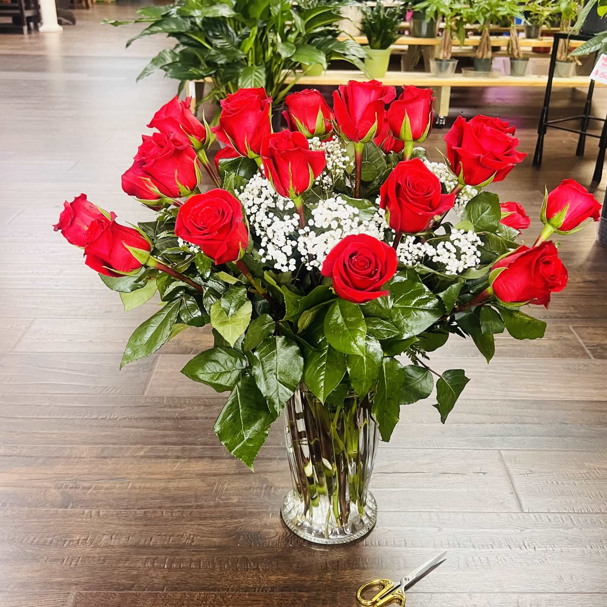 Red roses arranged in a clear glass vase with white filler flowers