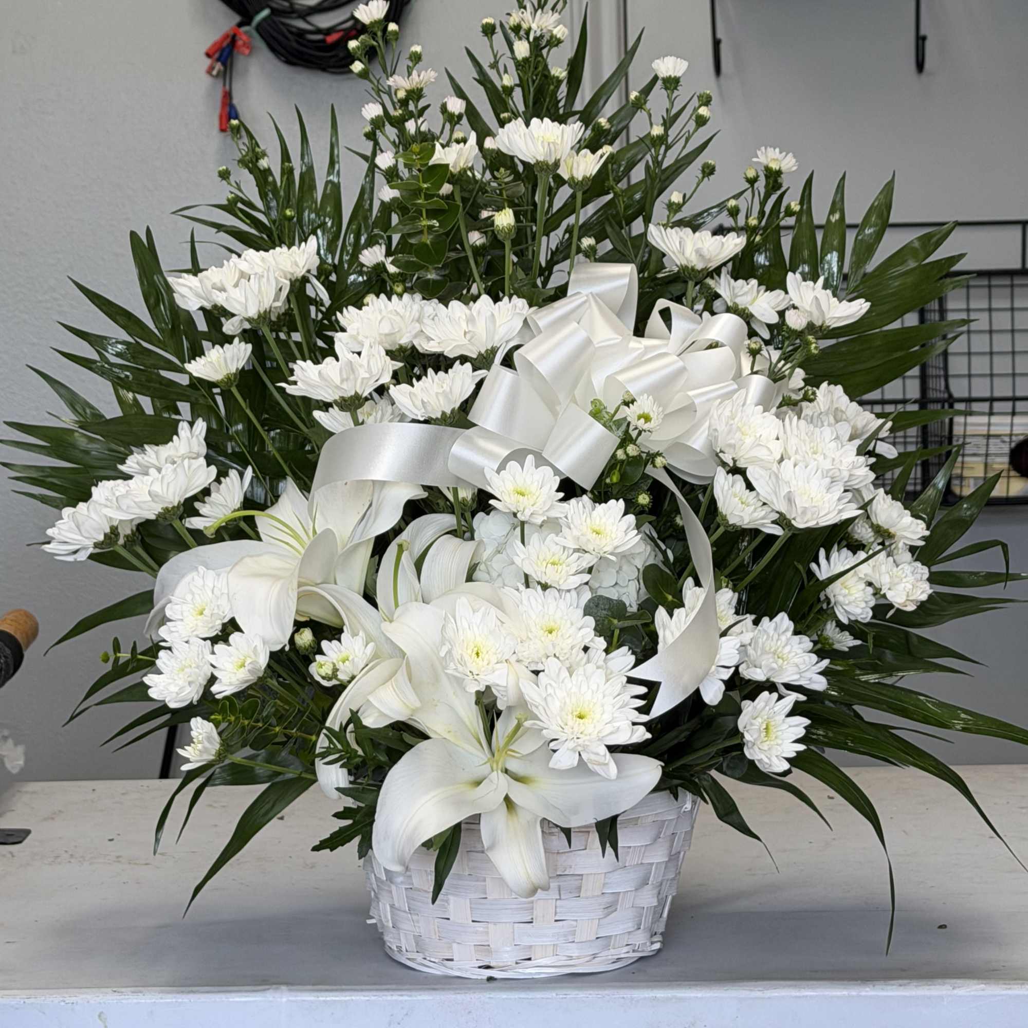 A calm cluster of white lilies and chrysanthemums arranged in a white