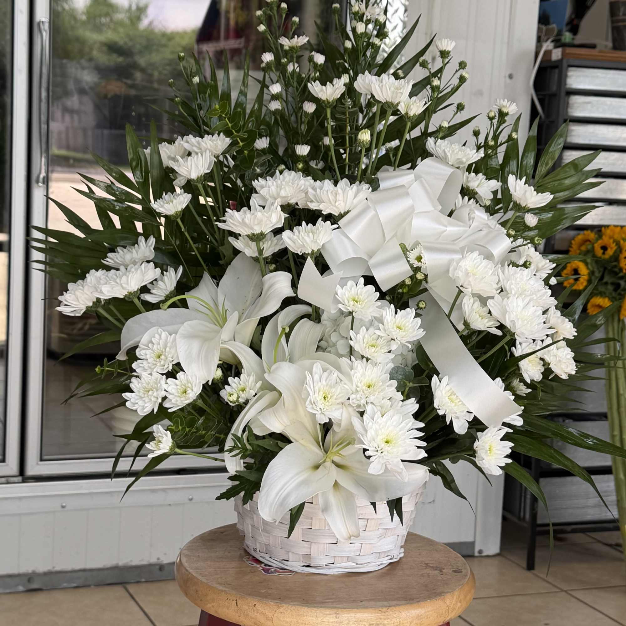 A calm cluster of white lilies and chrysanthemums arranged in a white