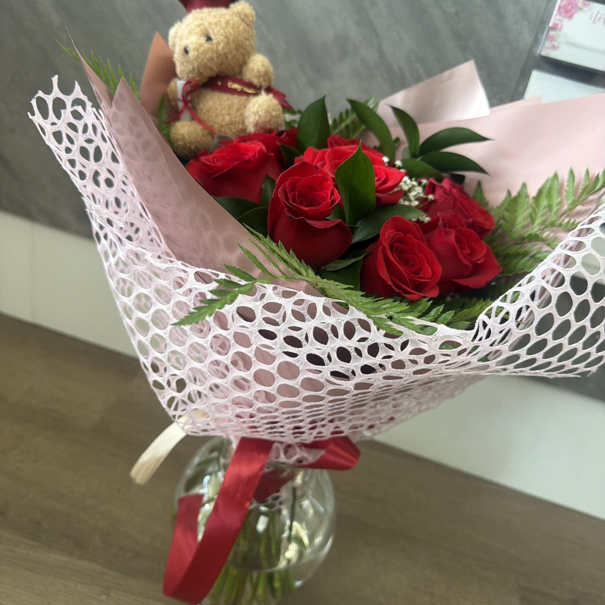 Bright, tightly clustered red roses form the heart of this graduation bouquet