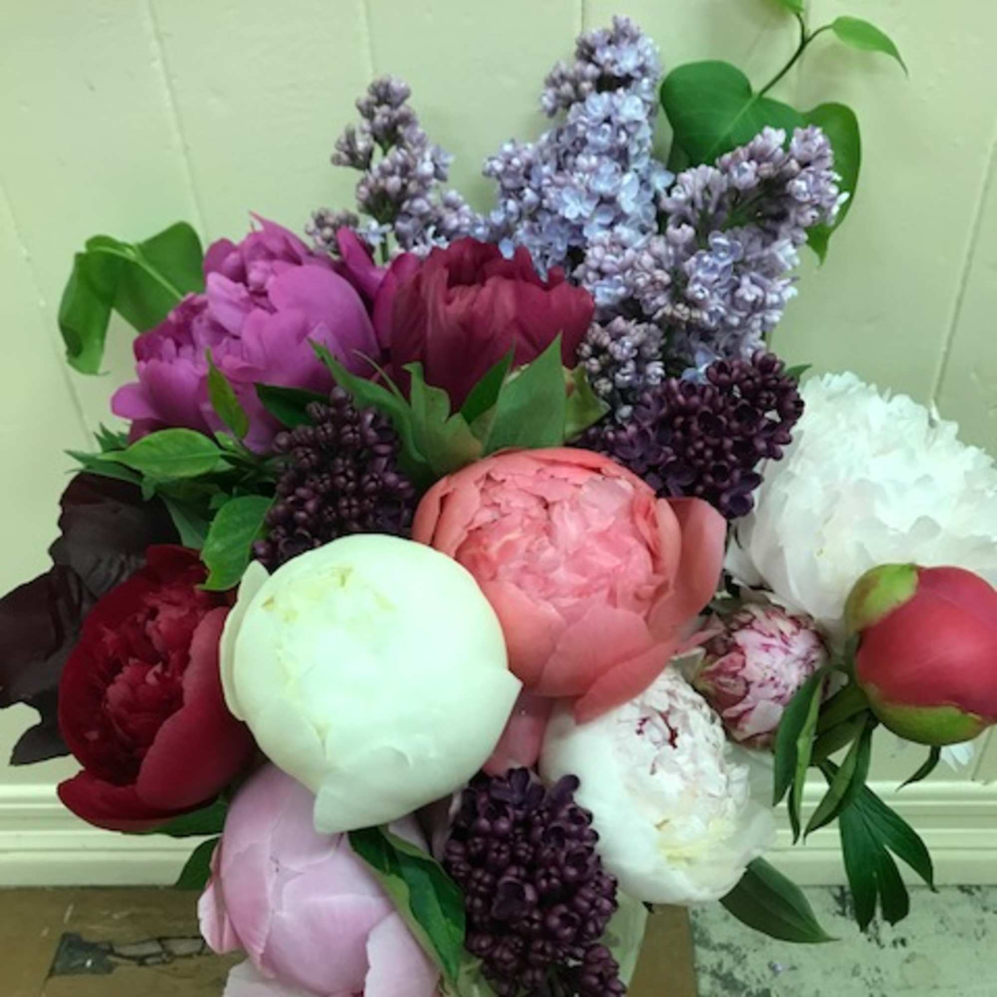 Bouquet of peonies and lilacs in a clear glass vase