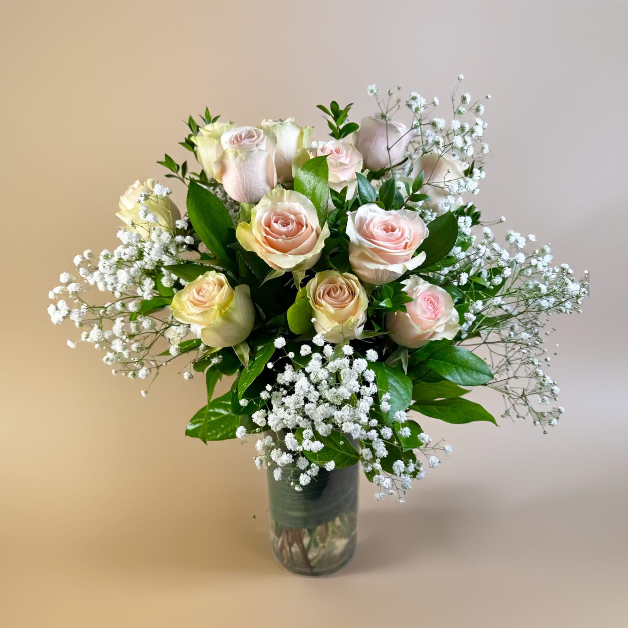 Bouquet of pale pink roses and baby's breath in a glass vase