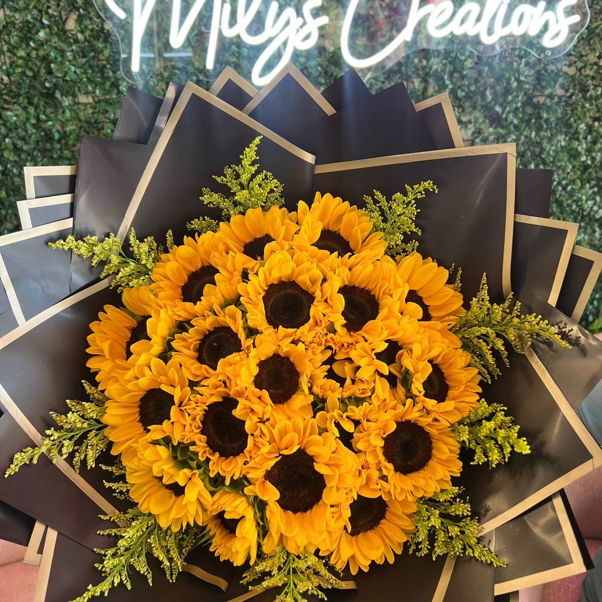 Bouquet of yellow sunflowers wrapped in black paper with gold trim