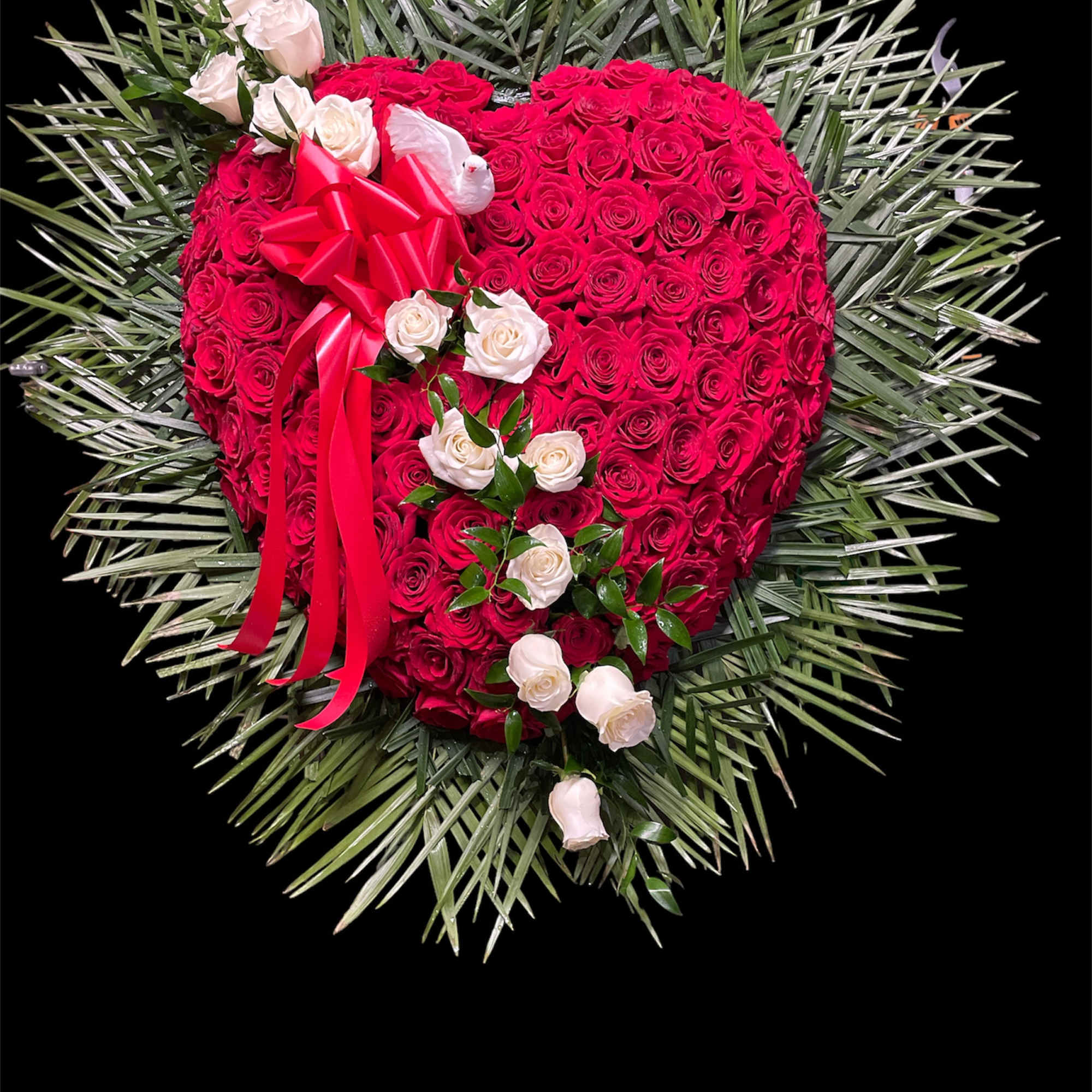 Heart-shaped red rose arrangement with white roses and a red ribbon