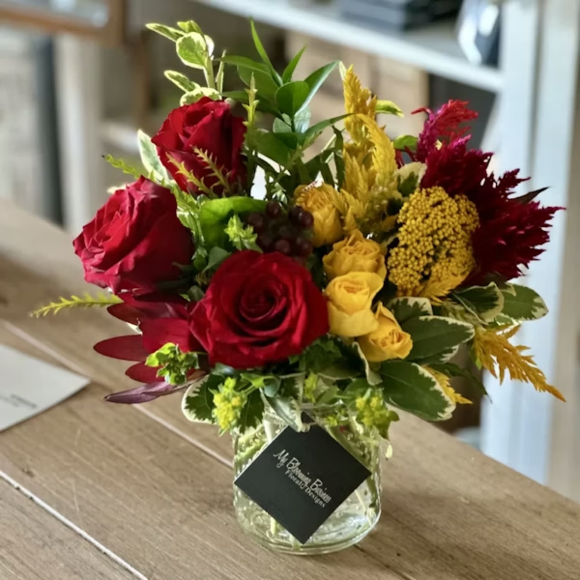 Red and yellow rose bouquet in a glass vase