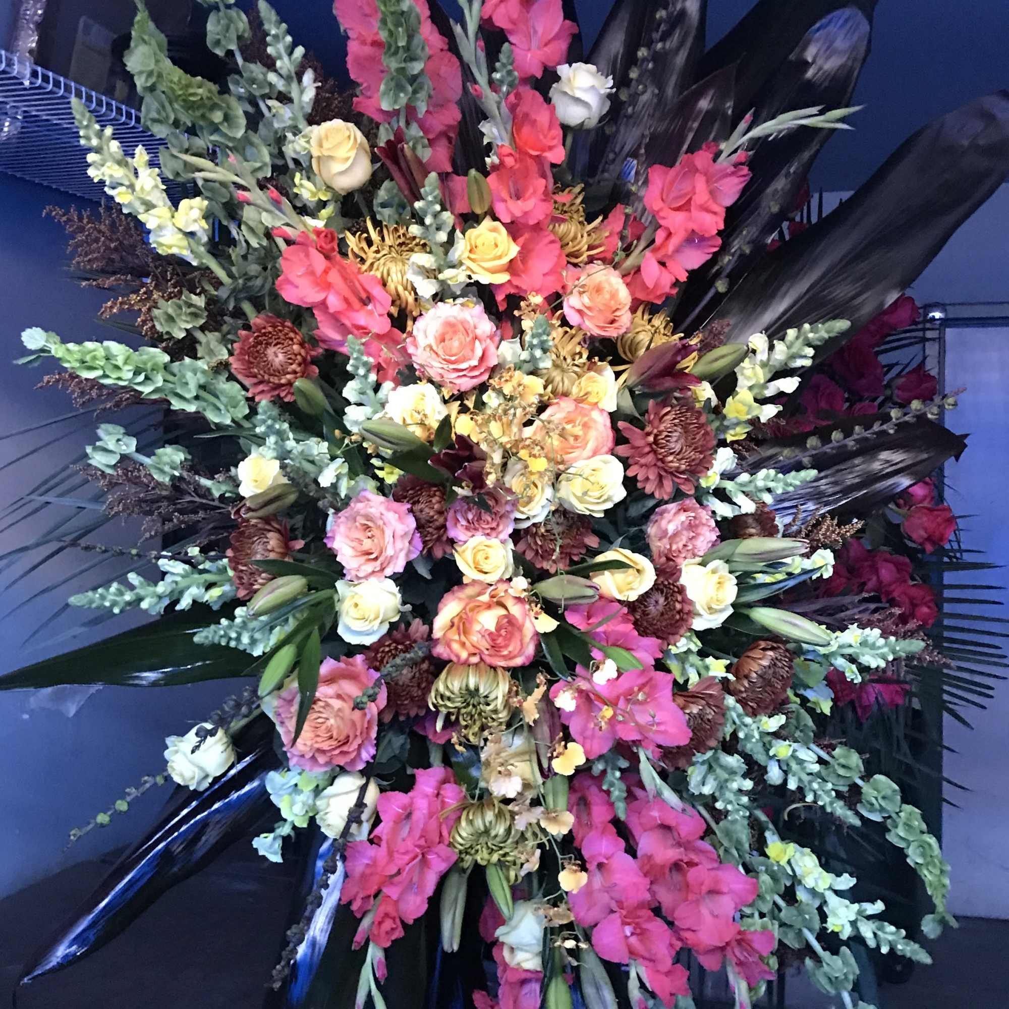 Large standing floral spray with pink and yellow flowers and black leaves