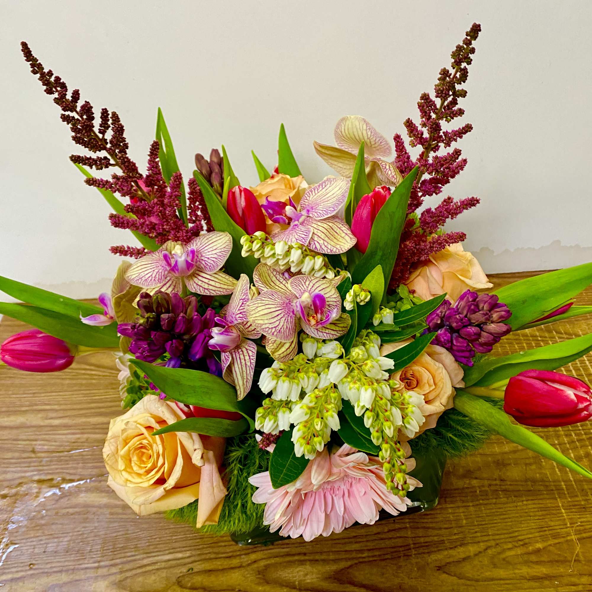 Mixed bouquet with peach roses, pink tulips, and purple orchids
