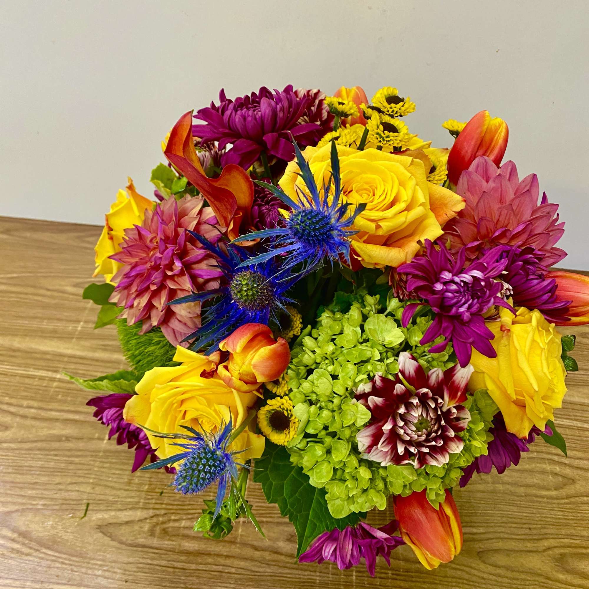 Bright mixed bouquet with yellow roses, magenta blooms, and blue thistles