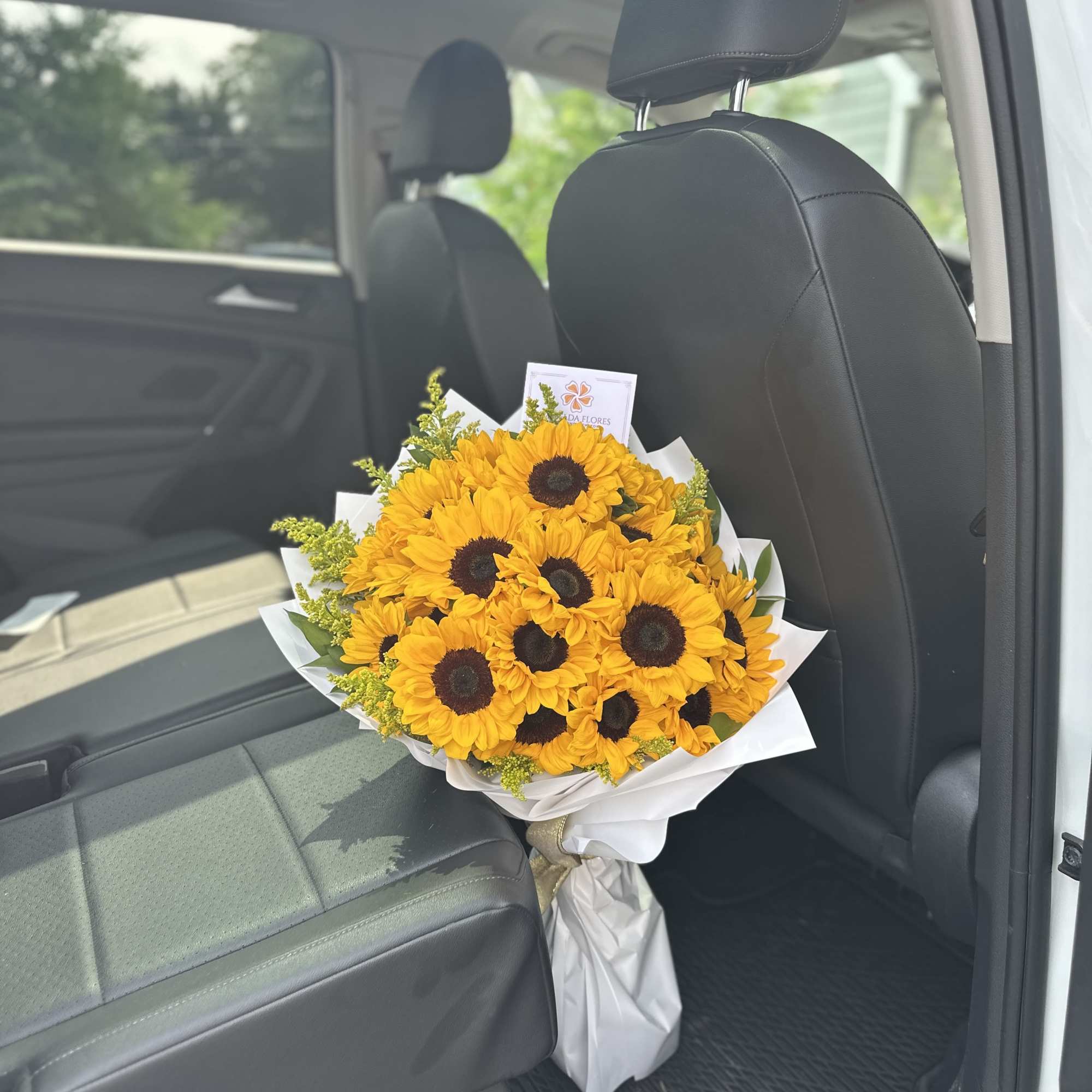 Bouquet of yellow sunflowers wrapped in white paper on a car seat