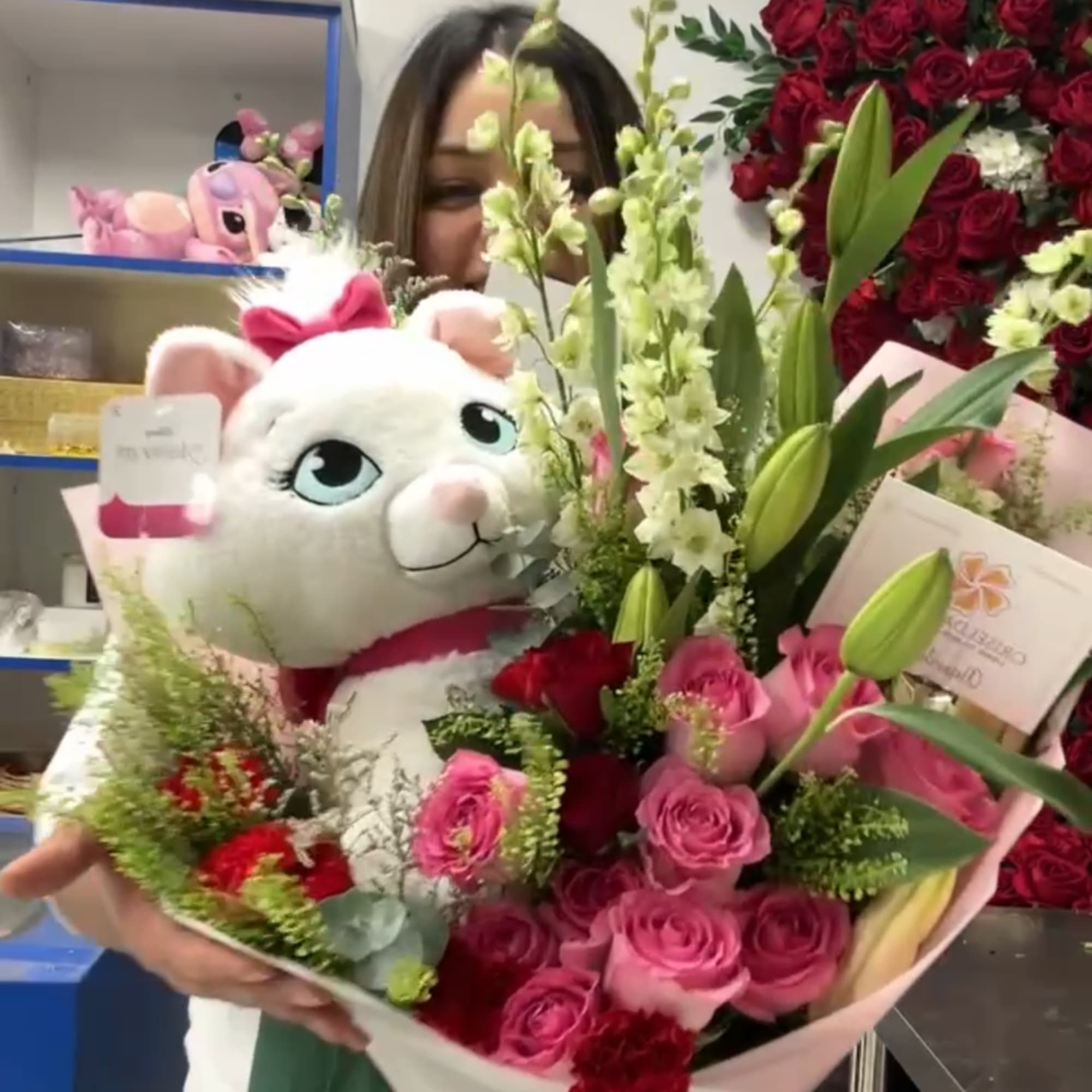 Bouquet of pink and red roses with lilies and a plush white cat
